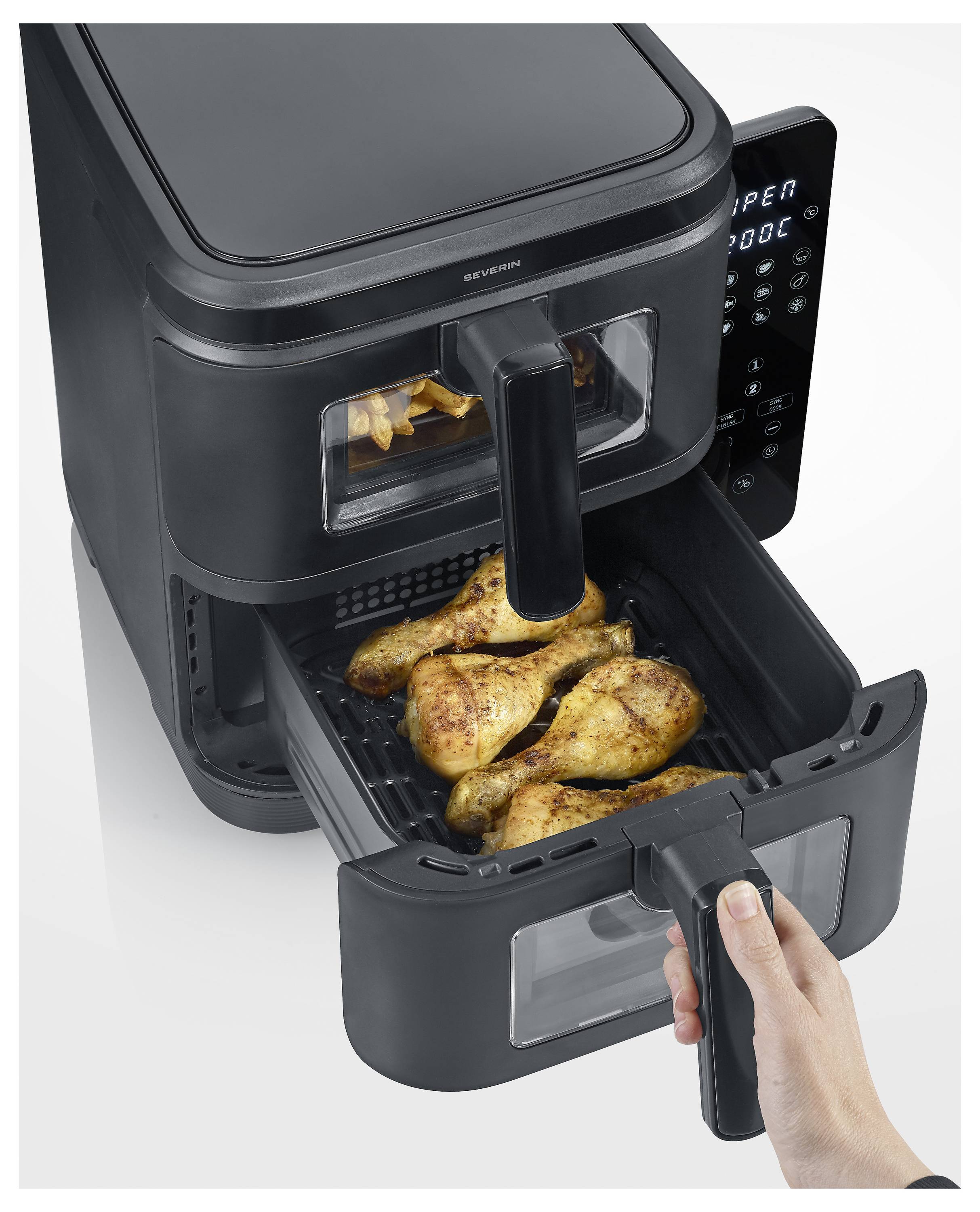 Un friggitrice ad aria con display digitale è mostrata con vassoi contenenti pollo cotto. Una mano sta tirando fuori uno dei vassoi.