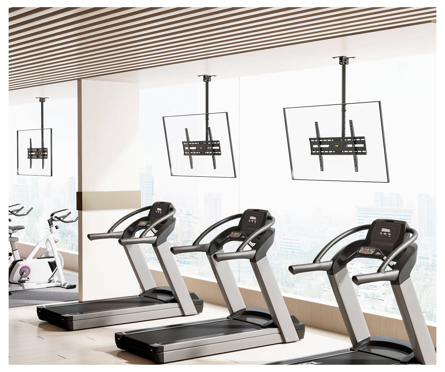 Una sala palestra con tre treadmill orientati verso una finestra, che si affacciano su uno skyline urbano. Due supporti TV montati a soffitto si trovano sopra i treadmill.