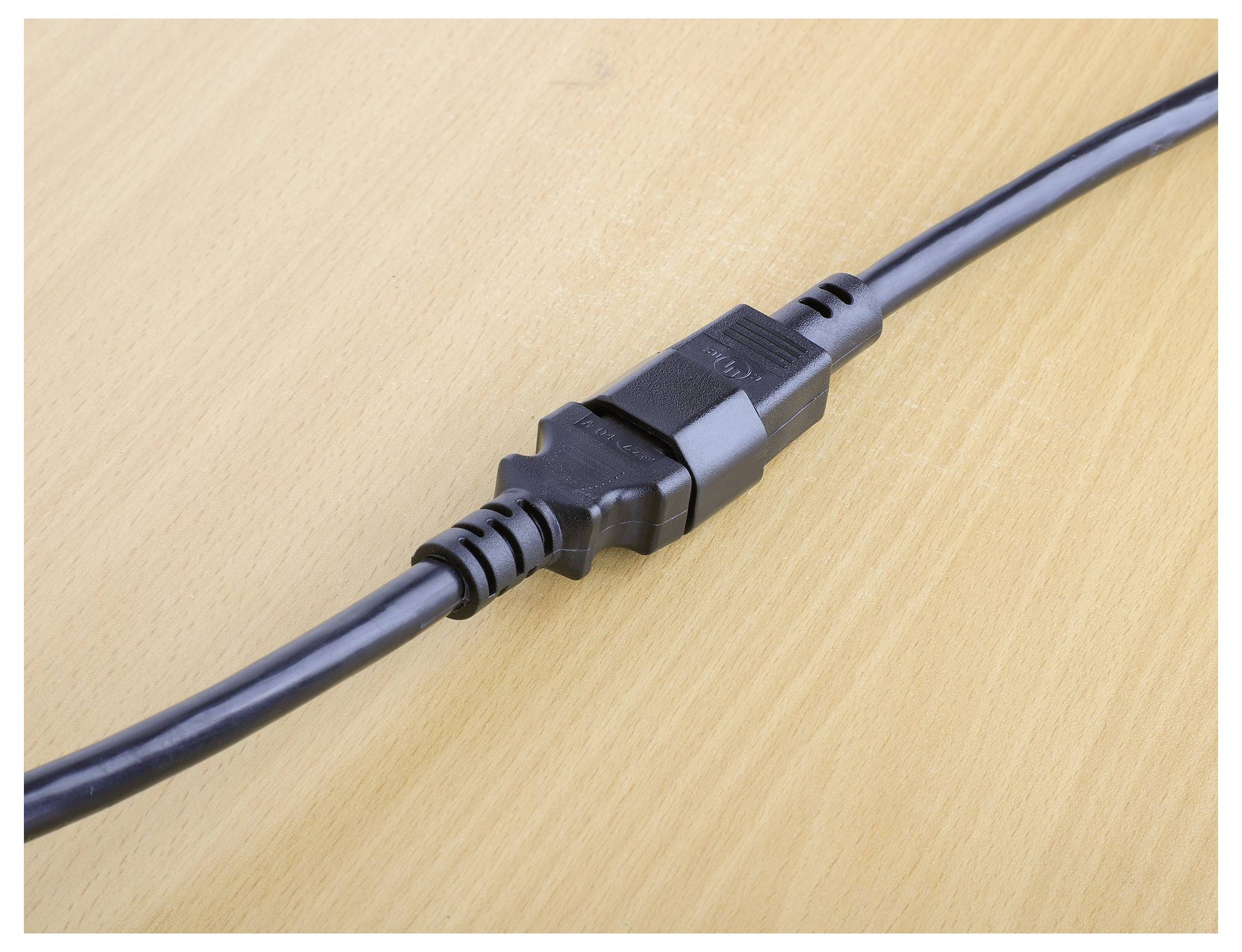 Un connettore di cavo di alimentazione nero bloccato in modo sicuro, posizionato su una superficie in legno chiaro, che mostra una vista ravvicinata del punto di connessione.