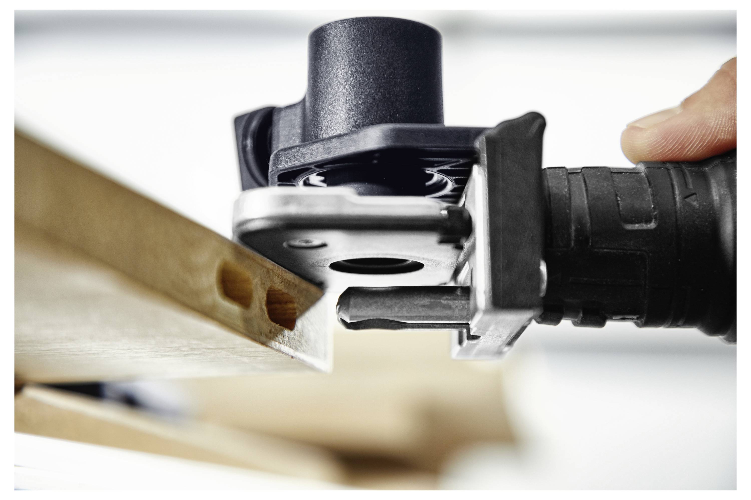 Una persona che utilizza un attrezzo elettrico nero e verde per avvitare viti in una parete, con una fila di viti allineate per l'alimentazione automatica.