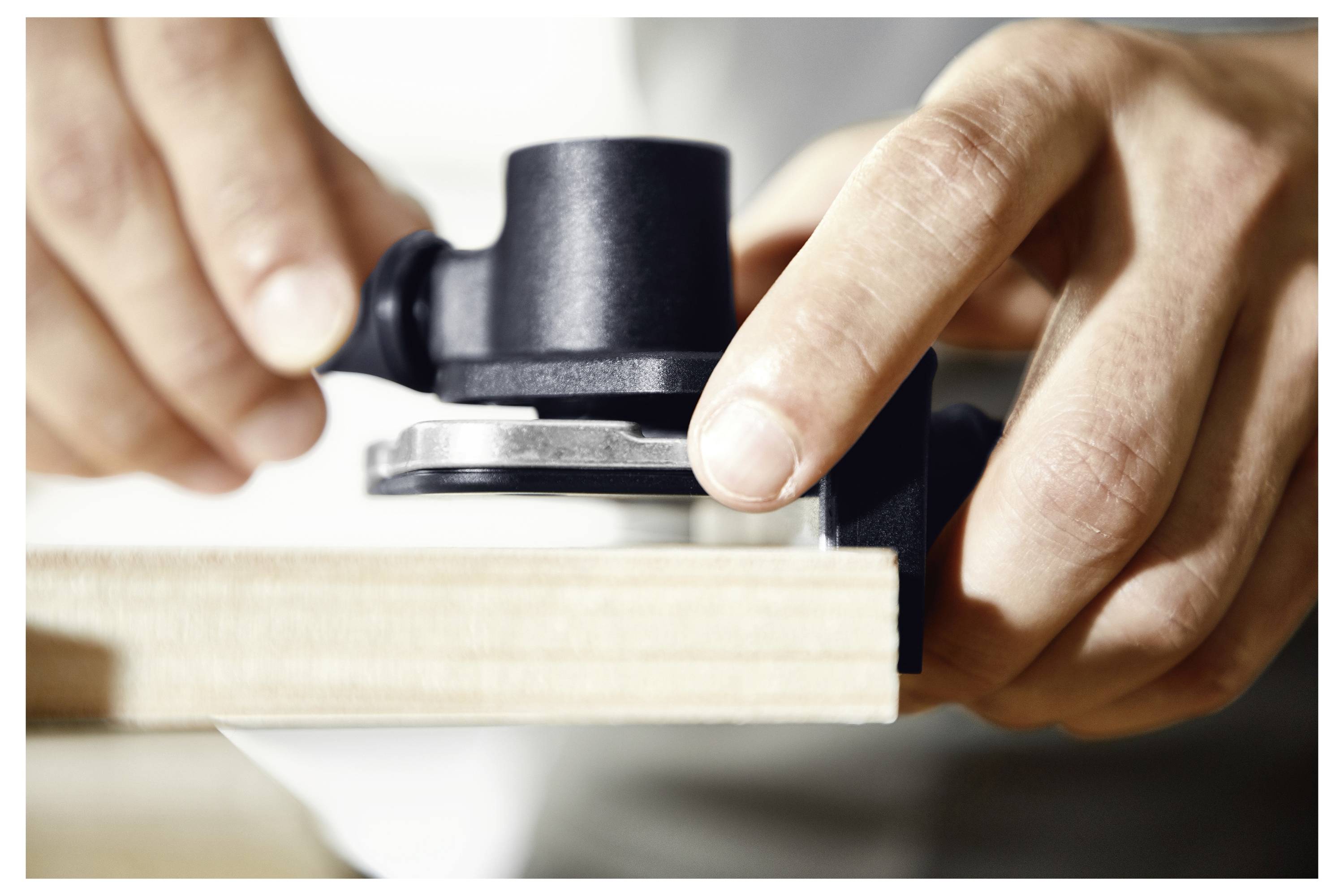 Una persona sta utilizzando uno strumento modello di cerniera nera sul bordo di una tavola di legno per la perforazione e l'adattamento precisi.