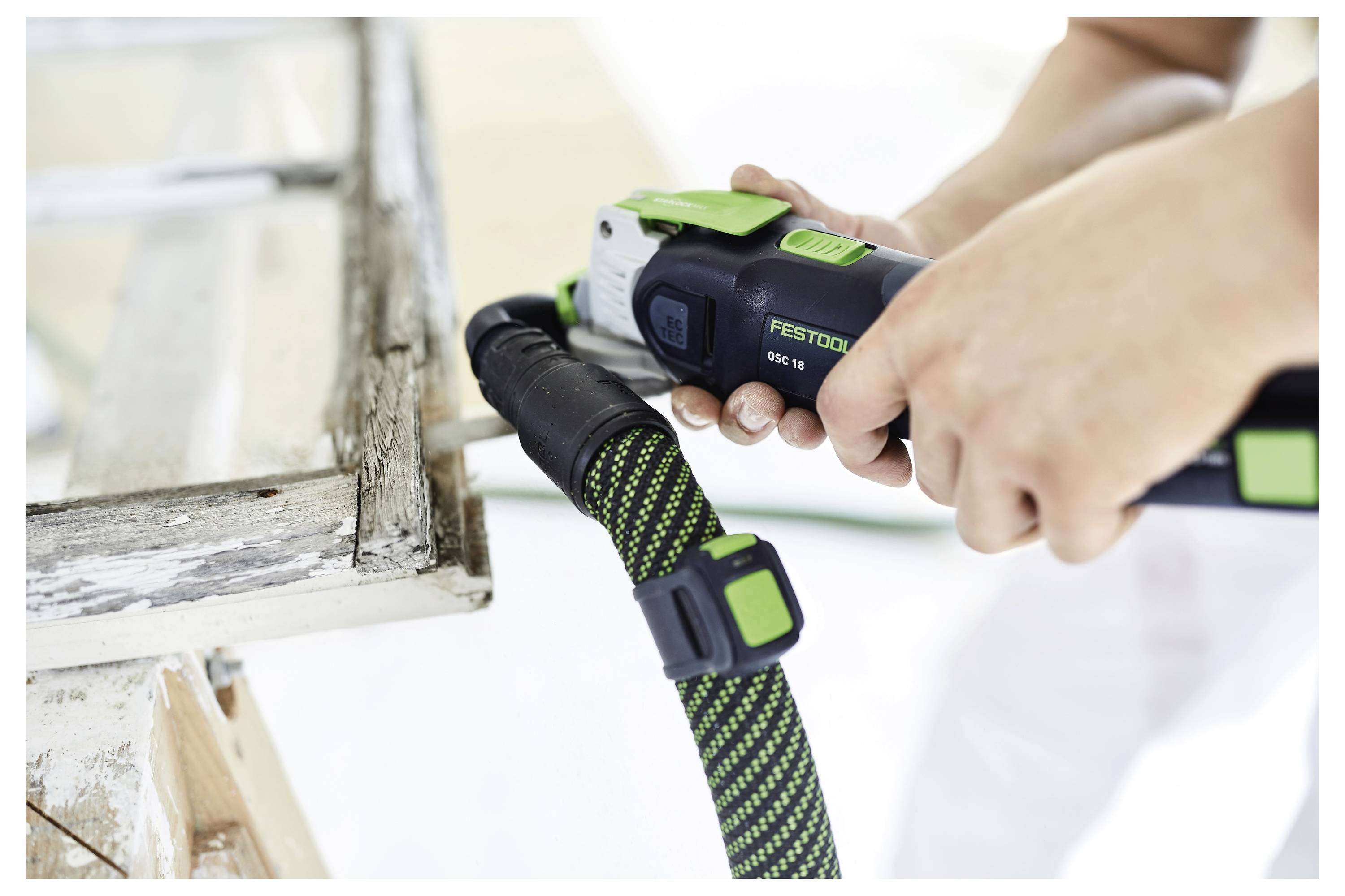 Persona che utilizza un utensile elettrico dal design verde e nero per levigare o lucidare un pezzo di arredamento in legno, concentrandosi sull'utensile e sull'azione.