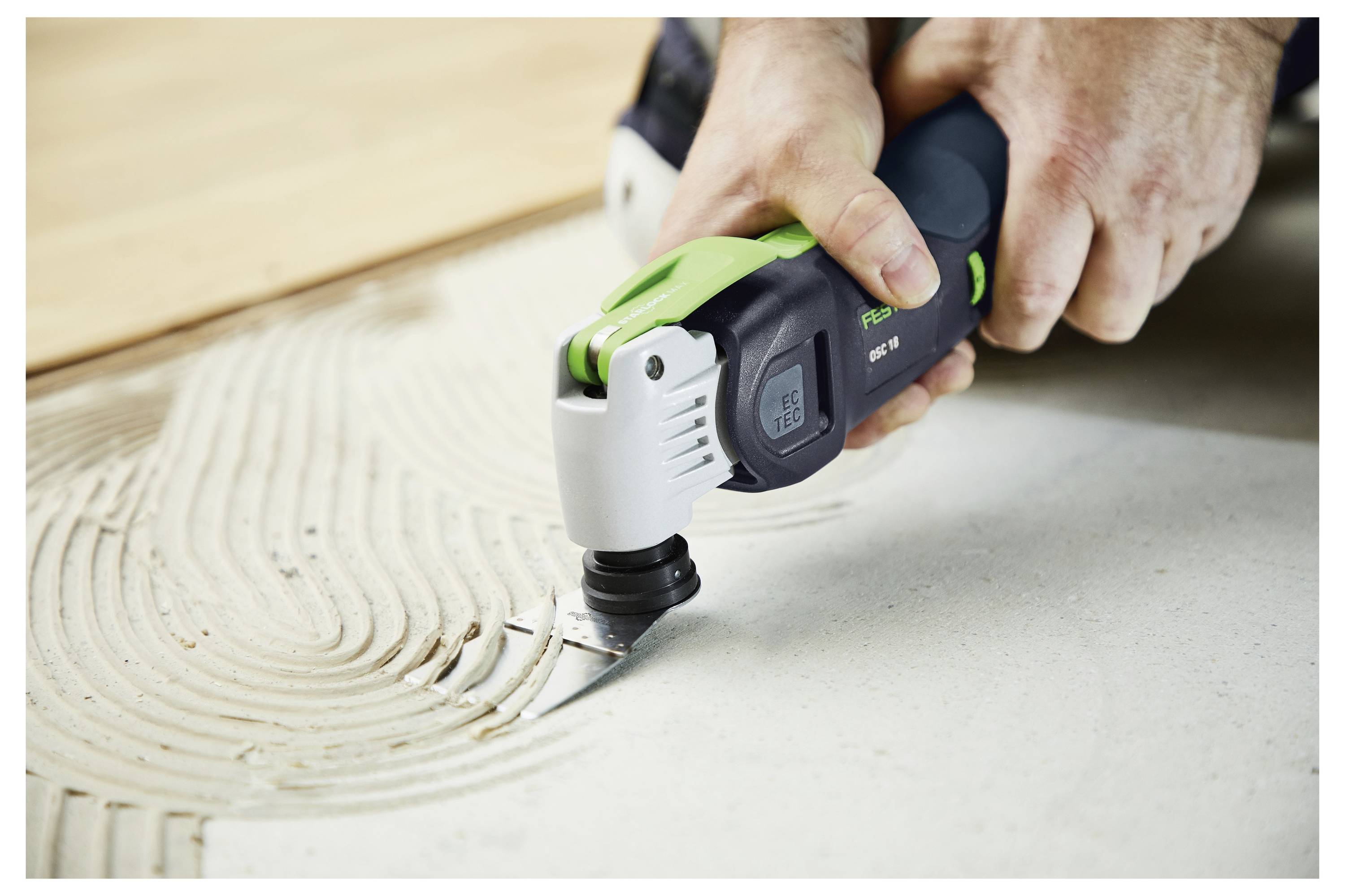 Una persona utilizza una levigatrice elettrica portatile per levigare il bordo di una ringhiera di scala in legno.