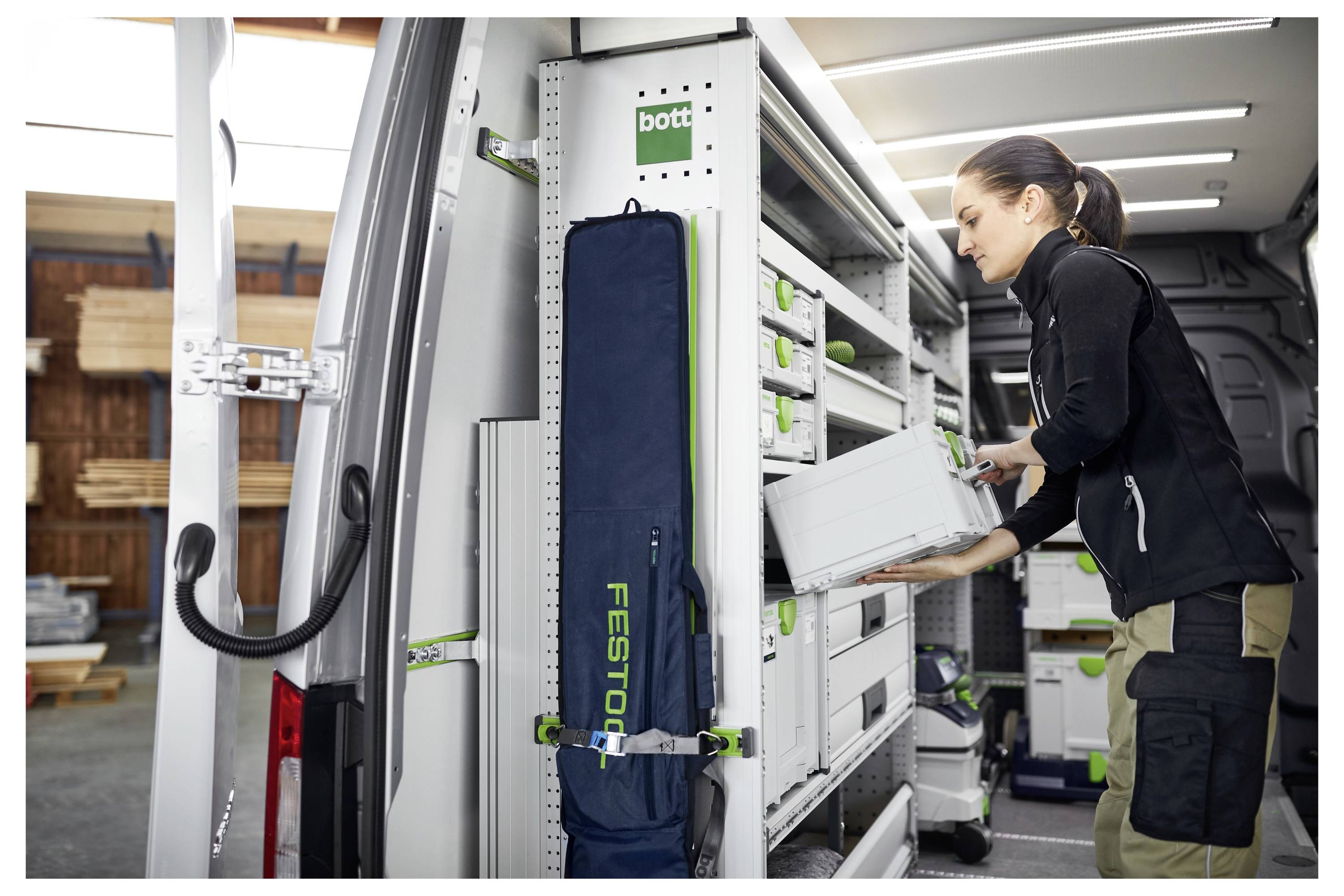 Una persona che organizza attrezzi in un furgone ben attrezzato, mostrando soluzioni di stoccaggio efficienti con scomparti etichettati e una varietà di equipaggiamento.