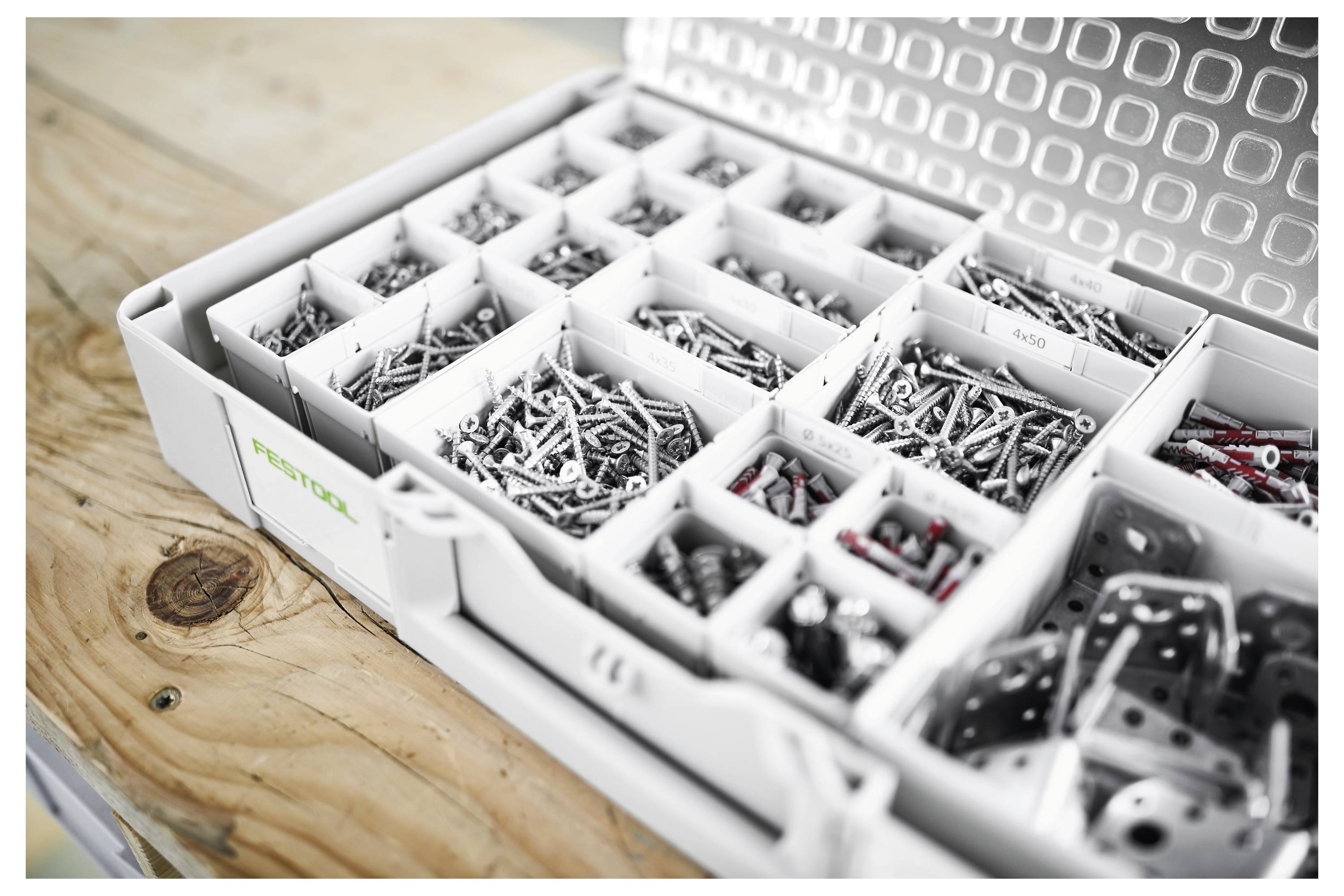 Un toolkit aperto con assorted viti metalliche e ferramenta organizzate in scomparti. La custodia è posizionata su un banco da lavoro in legno.