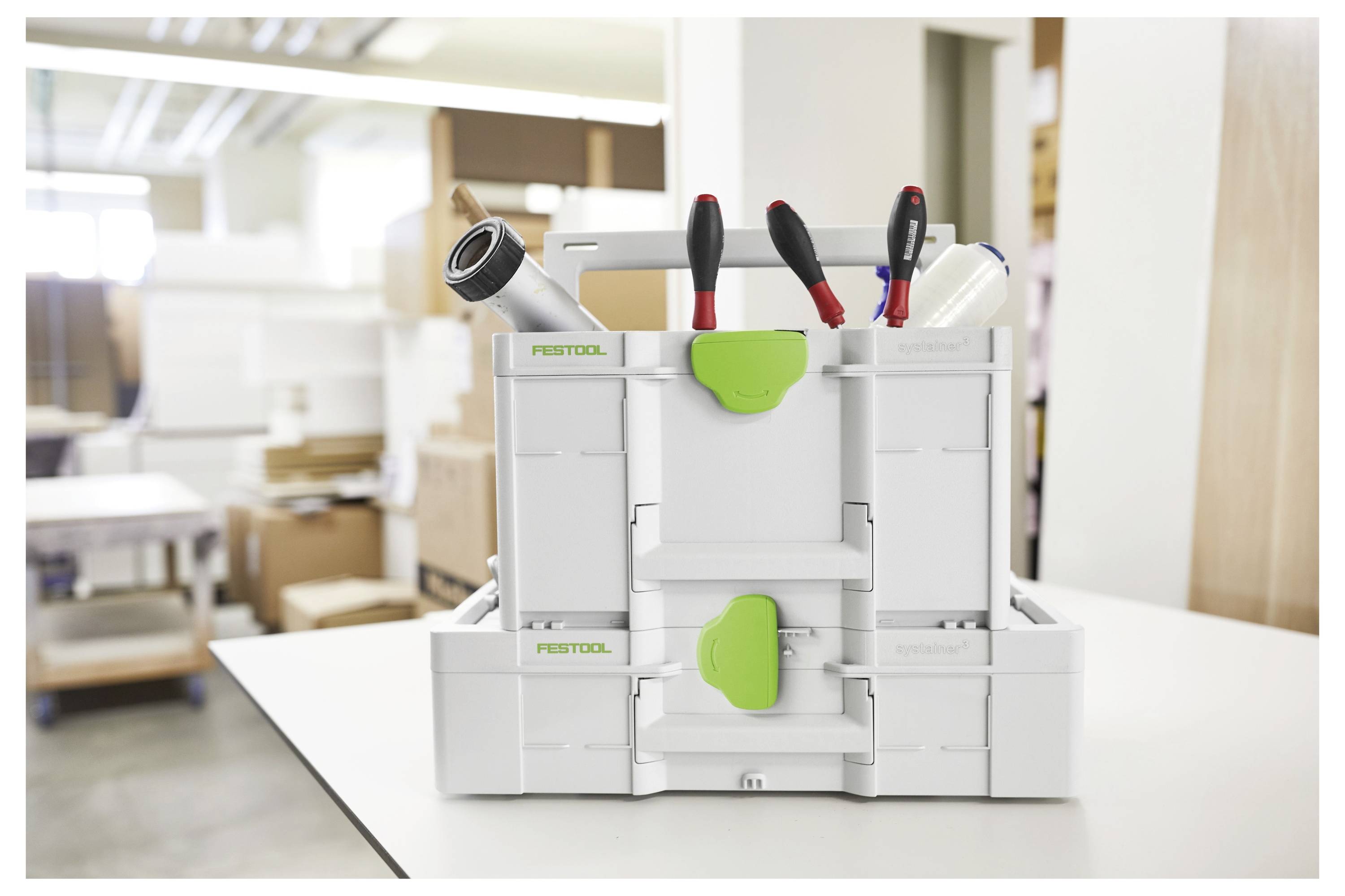 Una cassetta degli attrezzi con vari strumenti, inclusi pinze e cacciaviti, è posizionata su un tavolo in un ambiente di officina.