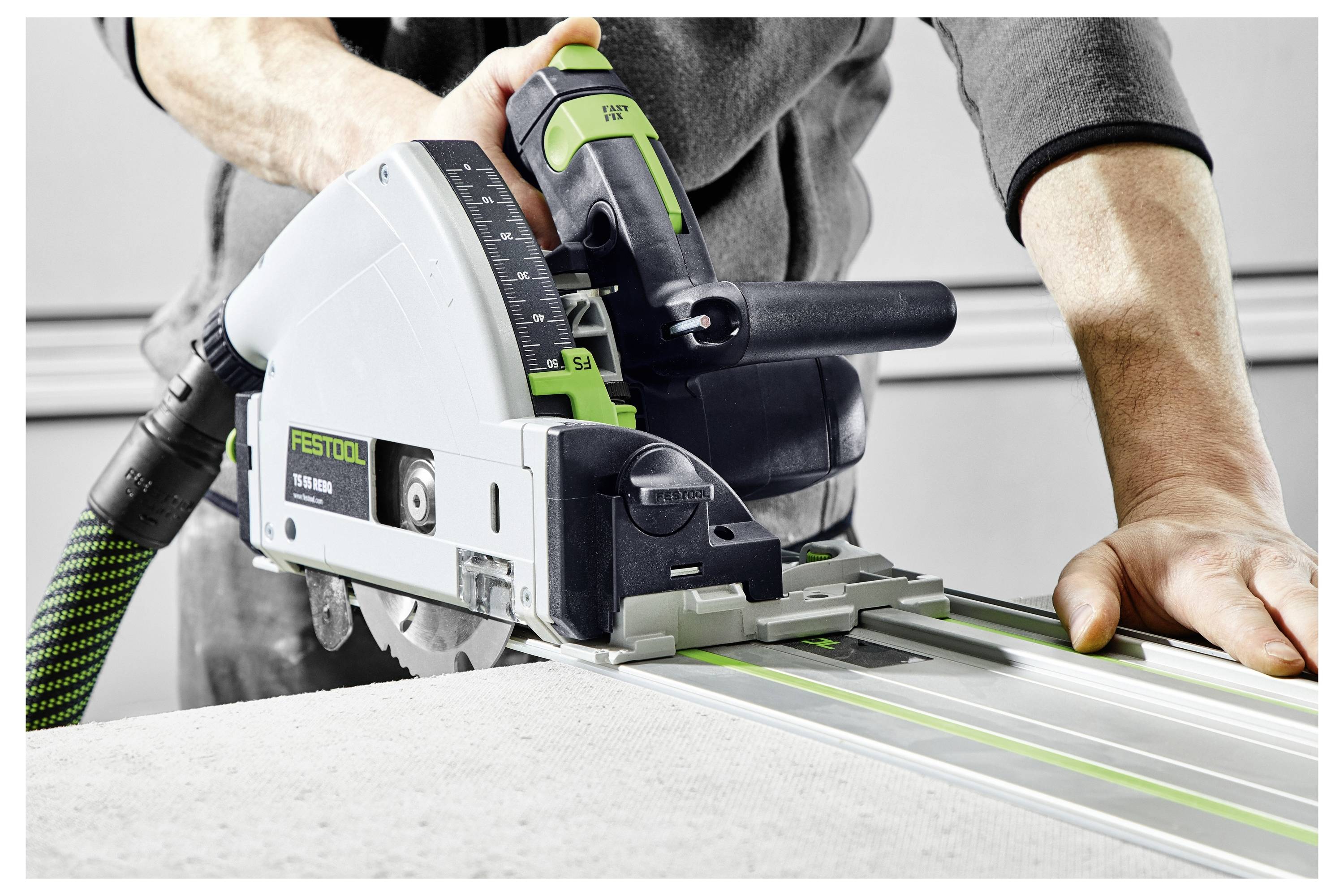 'Una persona che utilizza una sega a binario Festool per tagliare una tavola, dimostrando un taglio preciso con un sistema a binario guida in un ambiente di laboratorio.'