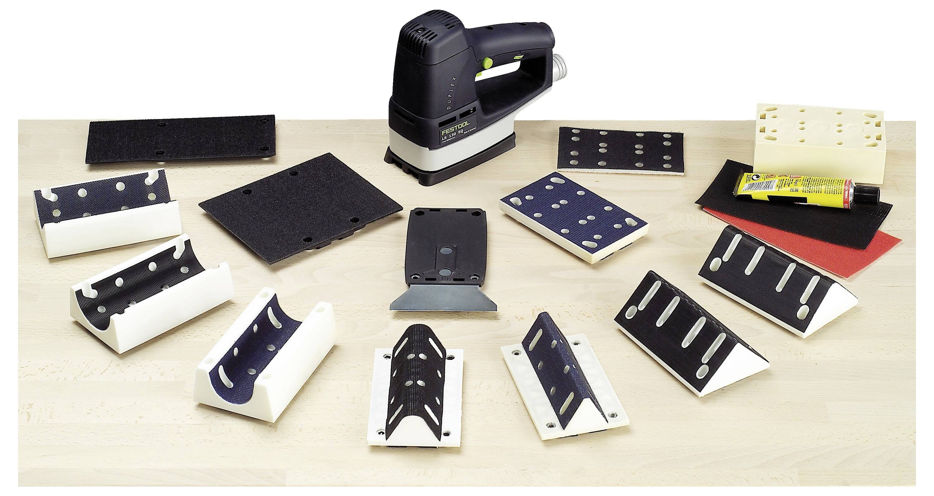 'Una levigatrice e numerosi accessori per la levigatura, inclusi vari dischi, blocchi e carte vetrate, sono disposti su una superficie in legno.'