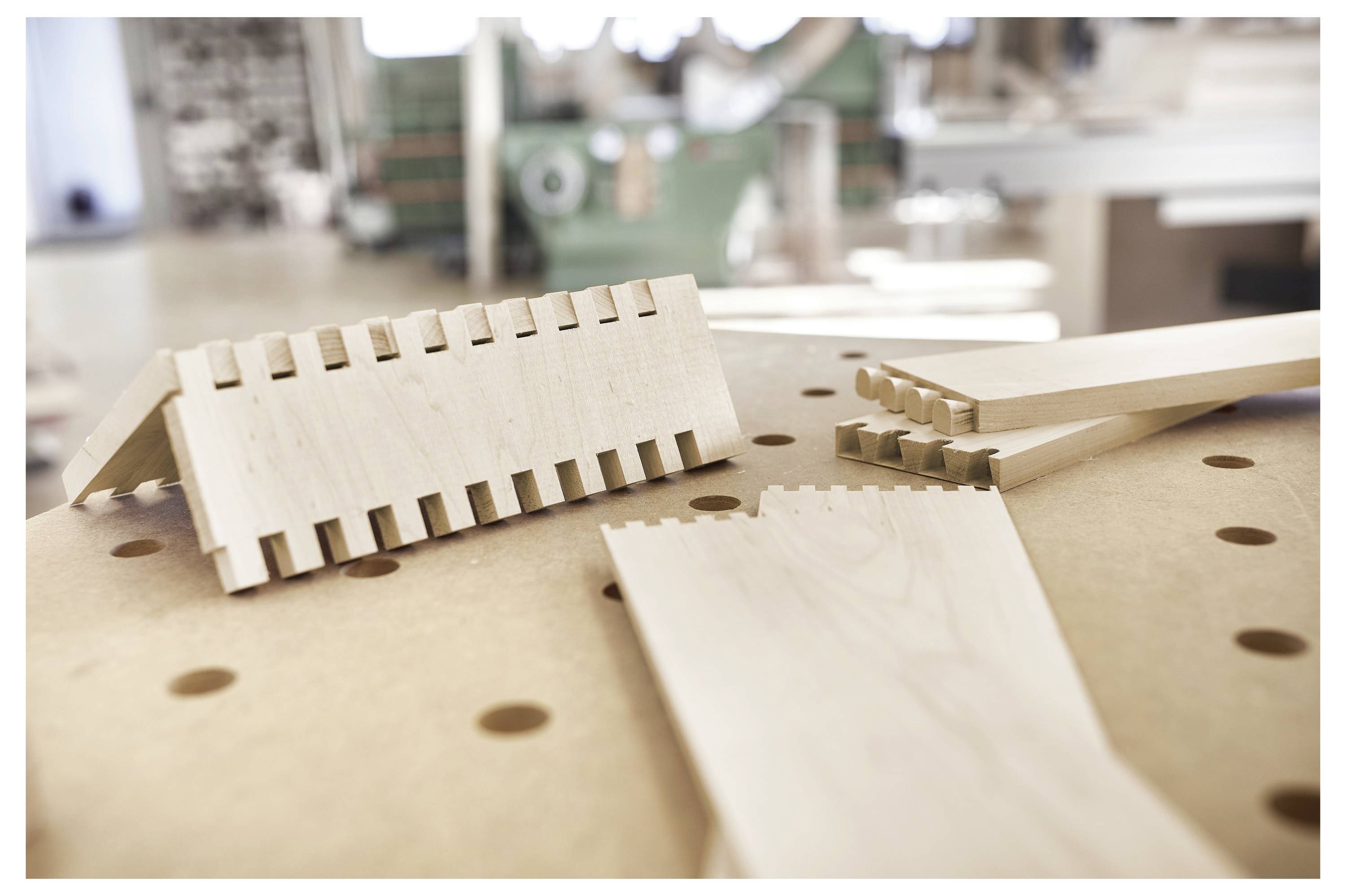 Assi di legno con giunti a coda di rondine interlacciati su un banco da lavoro, che suggeriscono lavori di falegnameria o carpenteria in corso.