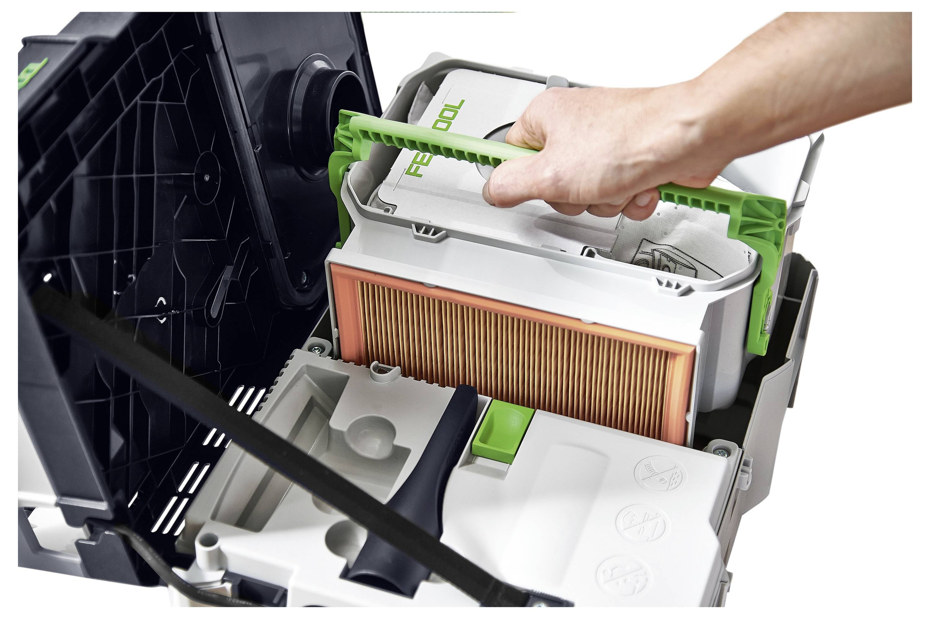 Una persona sostituisce un filtro antipolvere all'interno di un aspirapolvere, illustrando una procedura di manutenzione o pulizia. Una maniglia verde viene tirata.