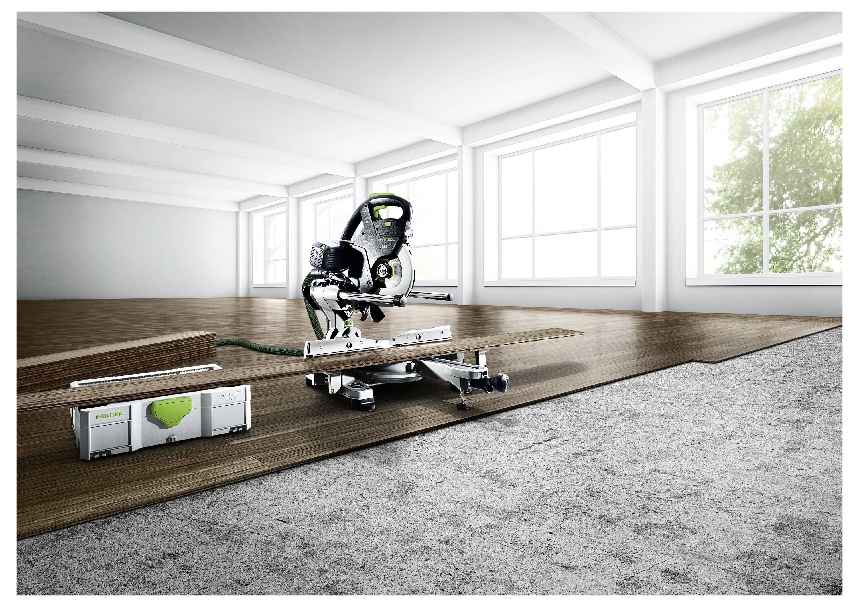 Una sega a ghigliottina su un supporto in una stanza luminosa e spaziosa. È posizionata su un pavimento in legno parzialmente installato, con una cassetta degli attrezzi nelle vicinanze.