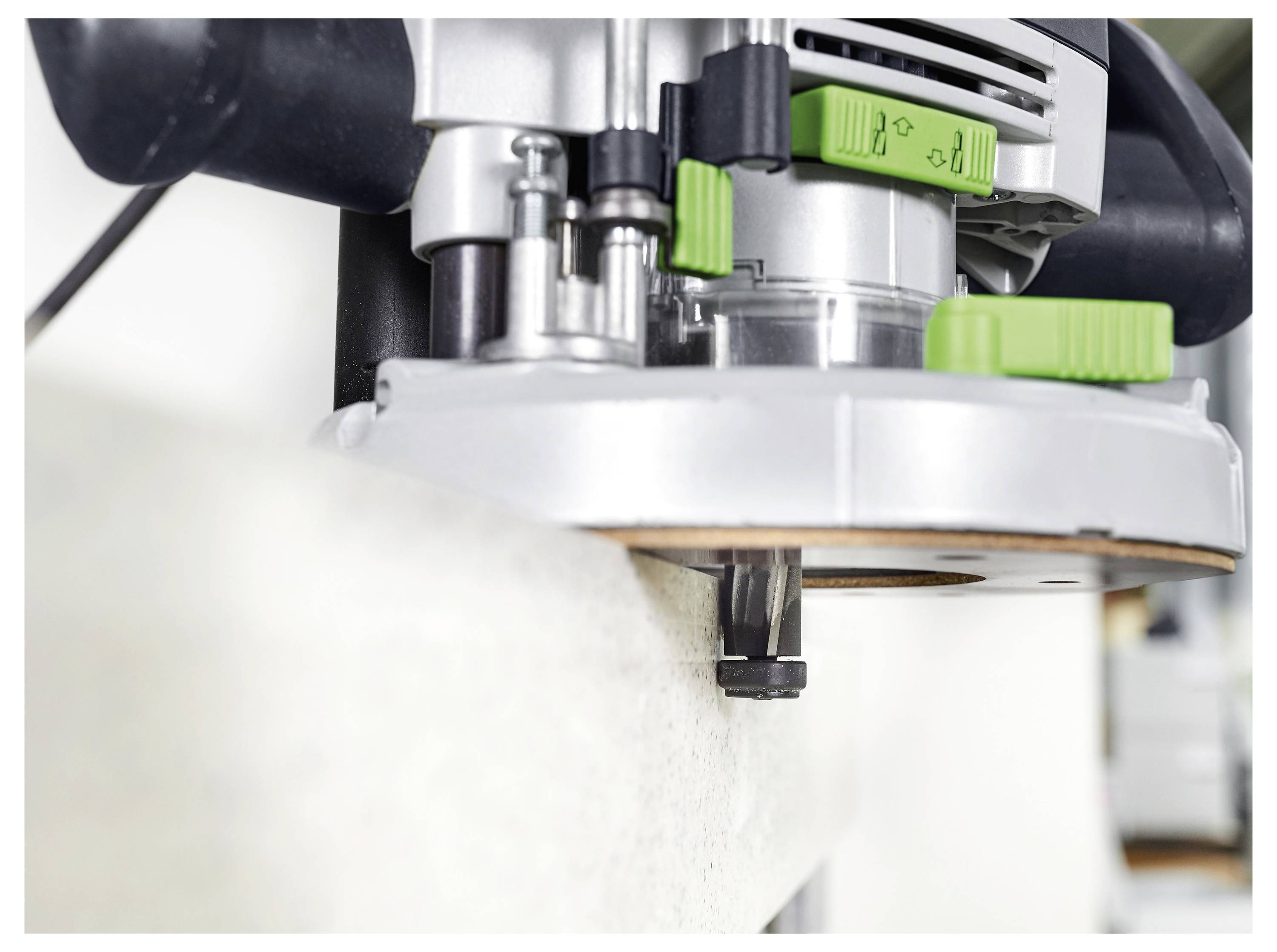 Una persona carteggia una parete bianca in una stanza in fase di ristrutturazione, utilizzando una macchina Festool collegata a un aspirapolvere, con grandi finestre sullo sfondo.