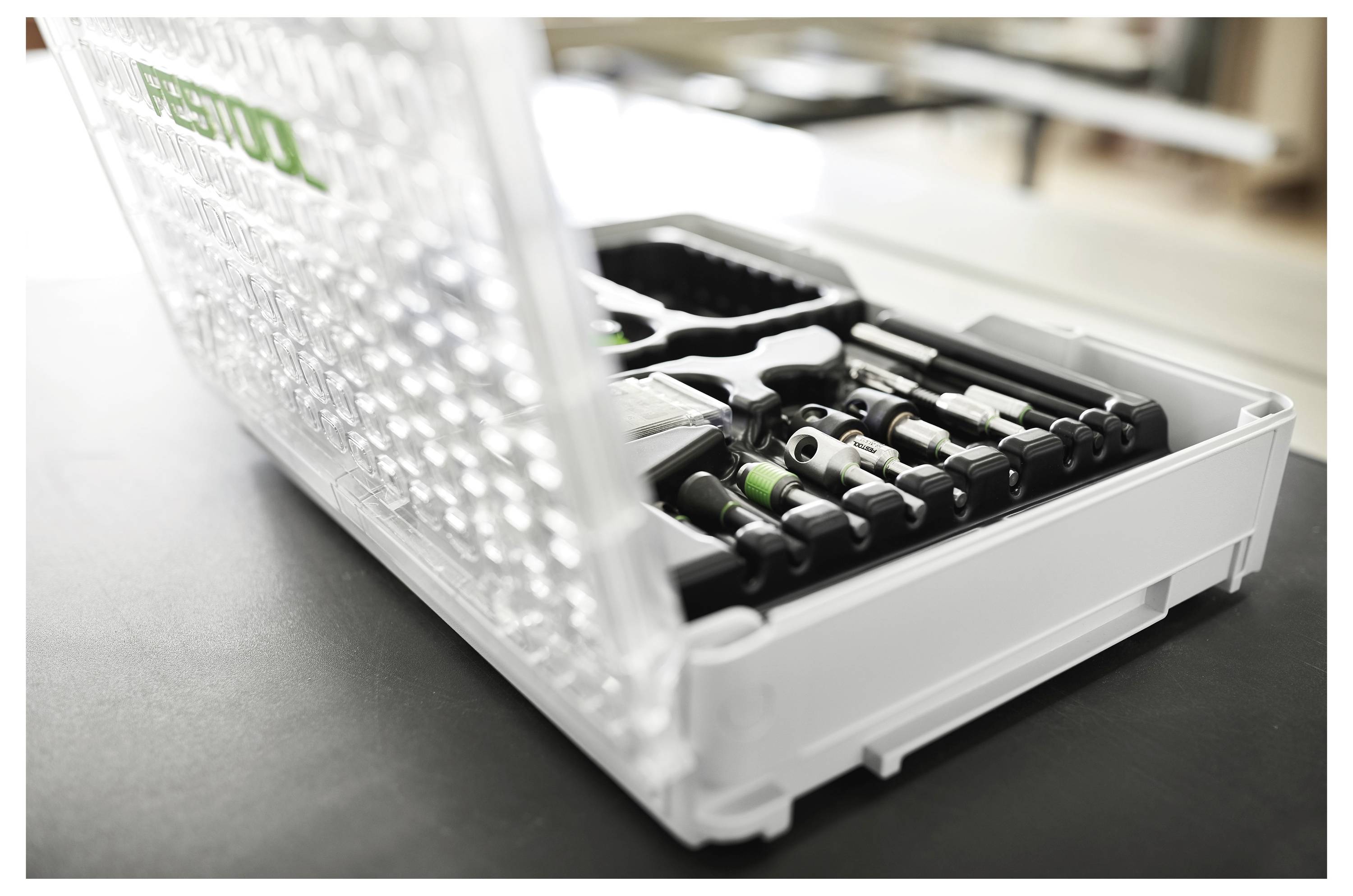 Una cassetta attrezzi aperta e trasparente con attrezzi ordinatamente disposti, inclusi cacciaviti, chiavi inglesi e un martello.