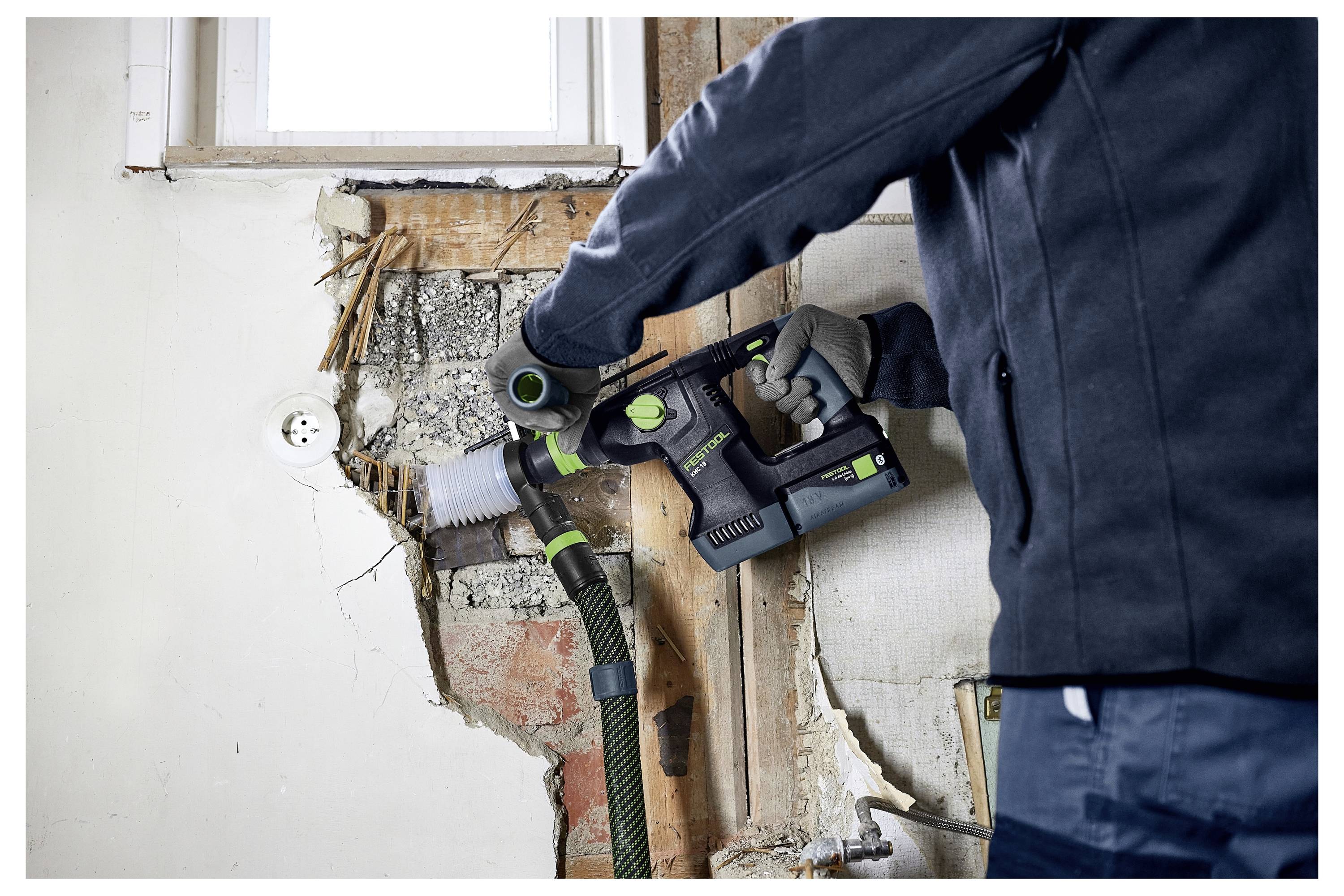 Una mano che carteggia una ringhiera in legno con una levigatrice elettrica, levigando la superficie del legno, evidenziando il processo di rifinitura.