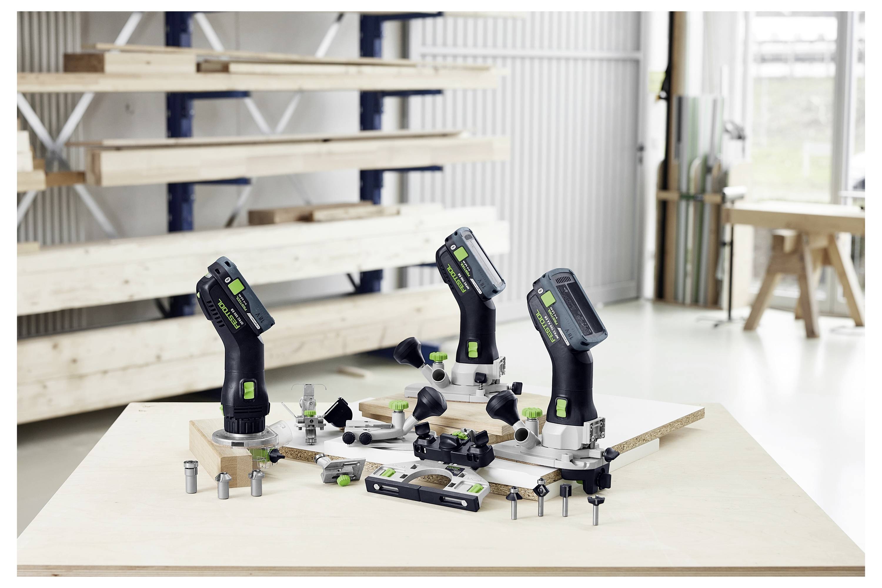 Una persona in un laboratorio che indossa una maglietta blu navy e pantaloncini con il logo 'Festool', sorridente, con attrezzi e unità di stoccaggio sullo sfondo.