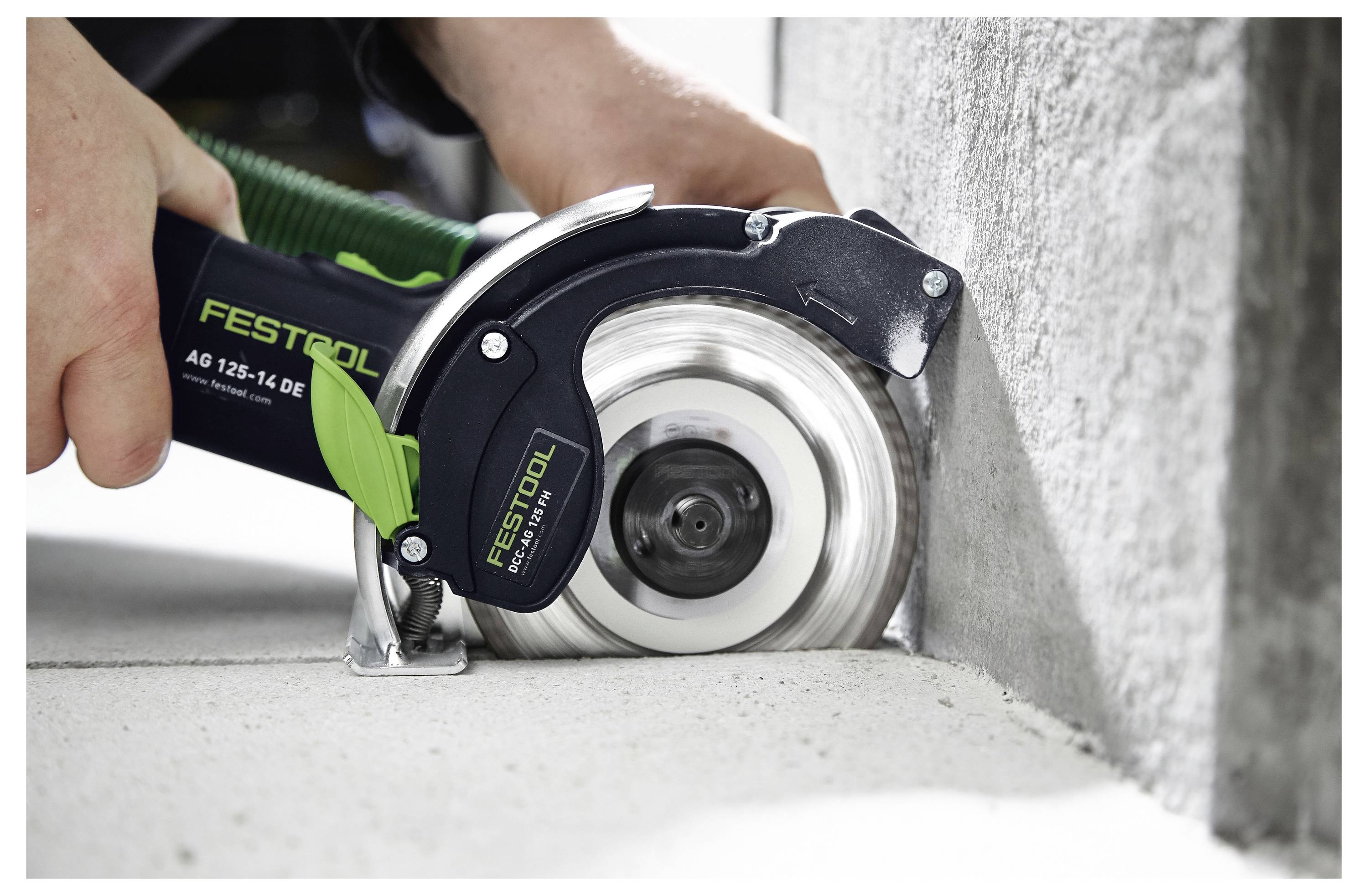Una persona che utilizza un attrezzo da taglio Festool per tagliare con precisione lungo un bordo di cemento.