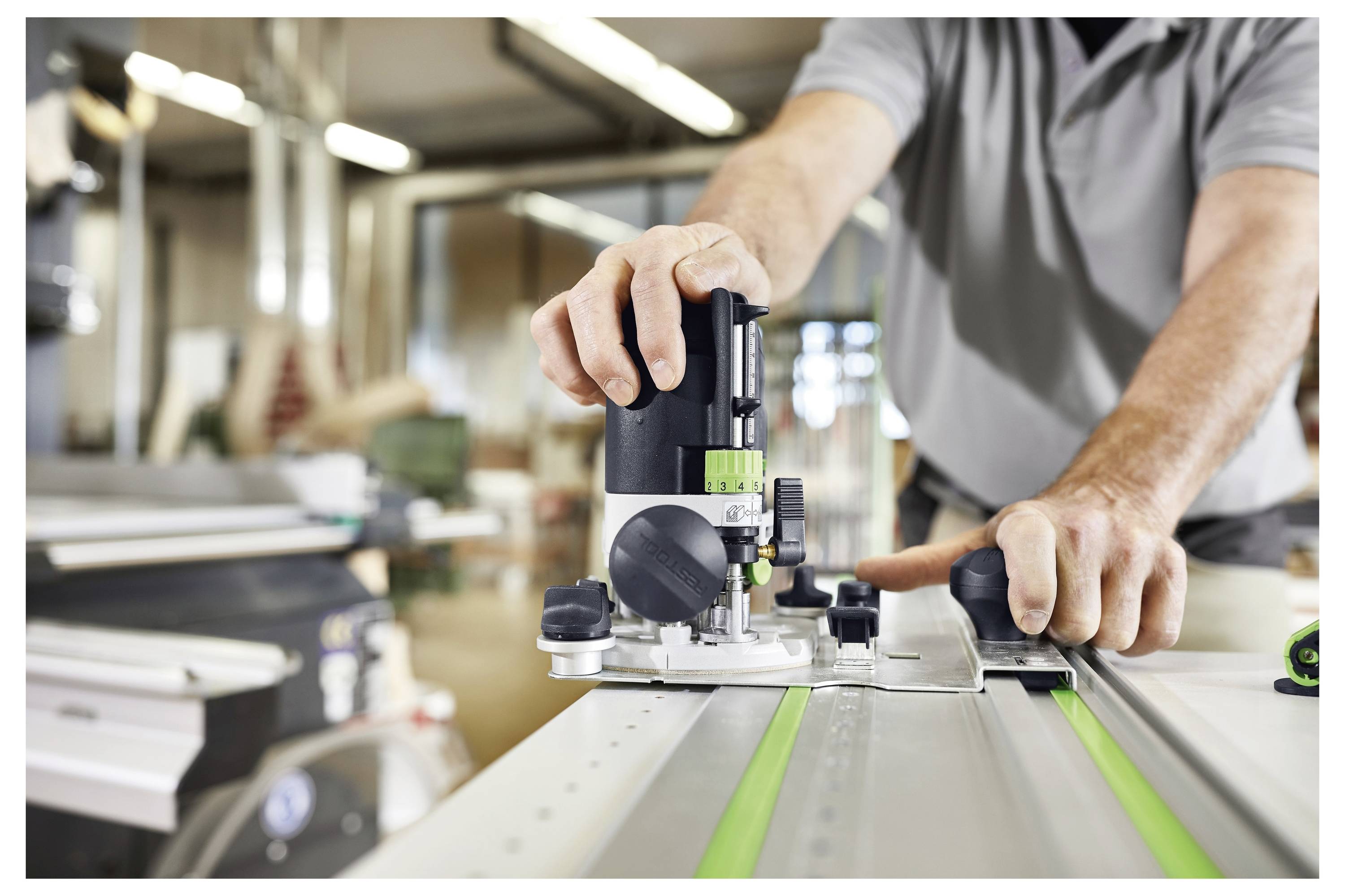 Un uomo in un cantiere prepara un pezzo di macchinario. Si trova su un pavimento in cemento con scale non finite e cavi elettrici nelle vicinanze.