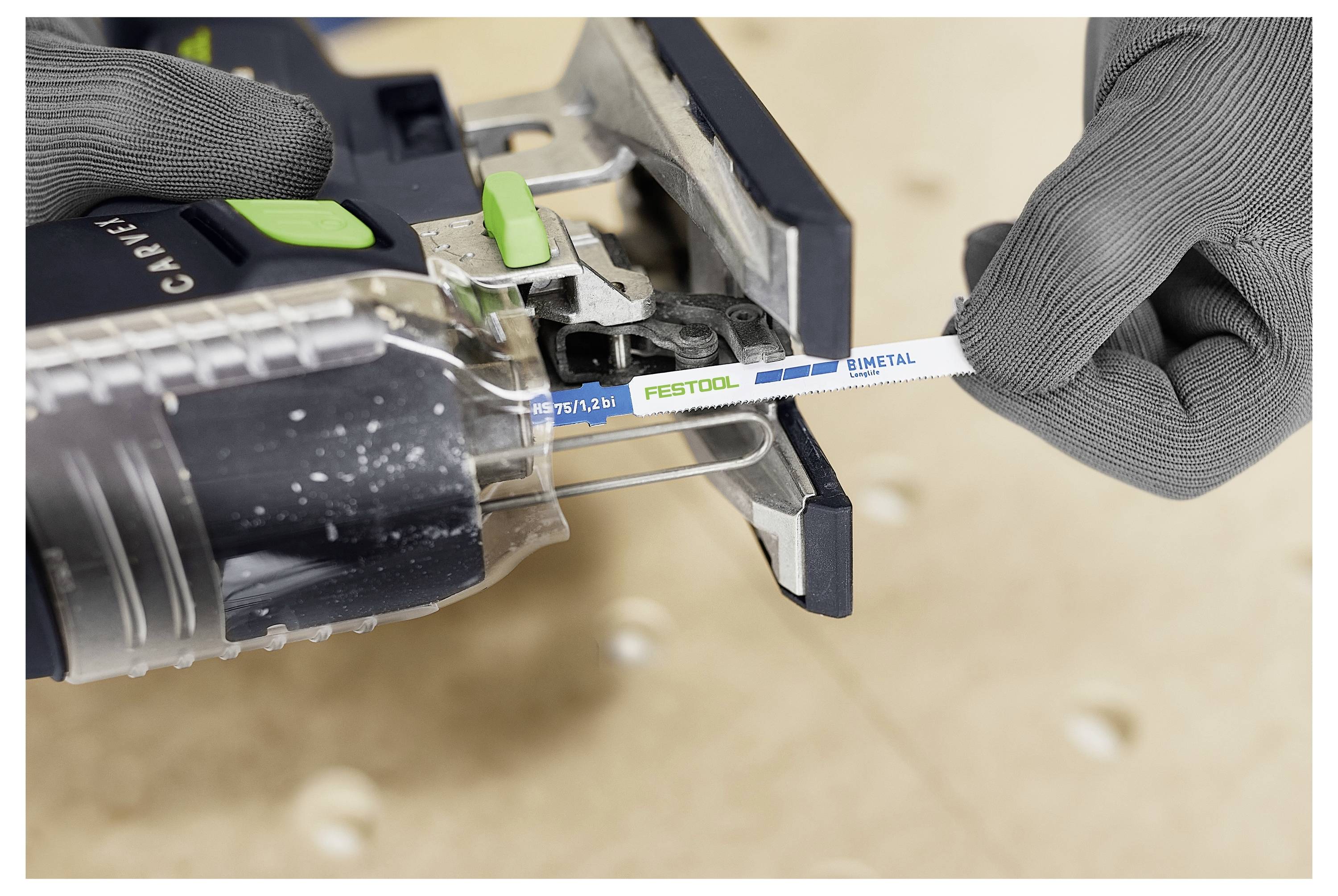 Una persona che indossa guanti inserisce una lama per seghetto alternativo Festool etichettata "Metallo" in uno strumento per seghetto alternativo, mostrando la manipolazione dell'attrezzo e l'impostazione della lama.