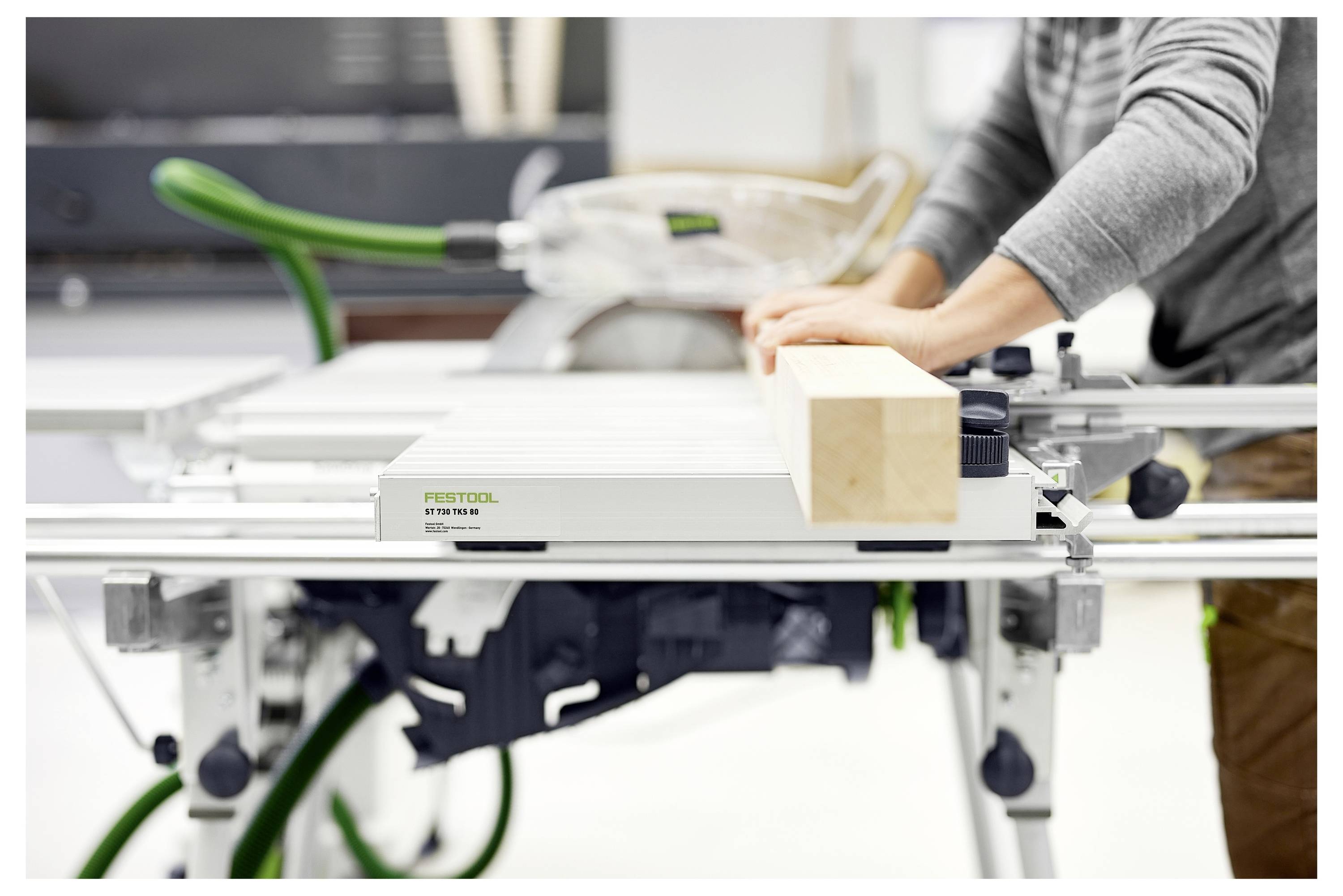 Persona che utilizza una sega circolare con tavolo scorrevole per tagliare una trave di legno, mostrando la gestione precisa degli attrezzi per la lavorazione del legno in un ambiente di officina.