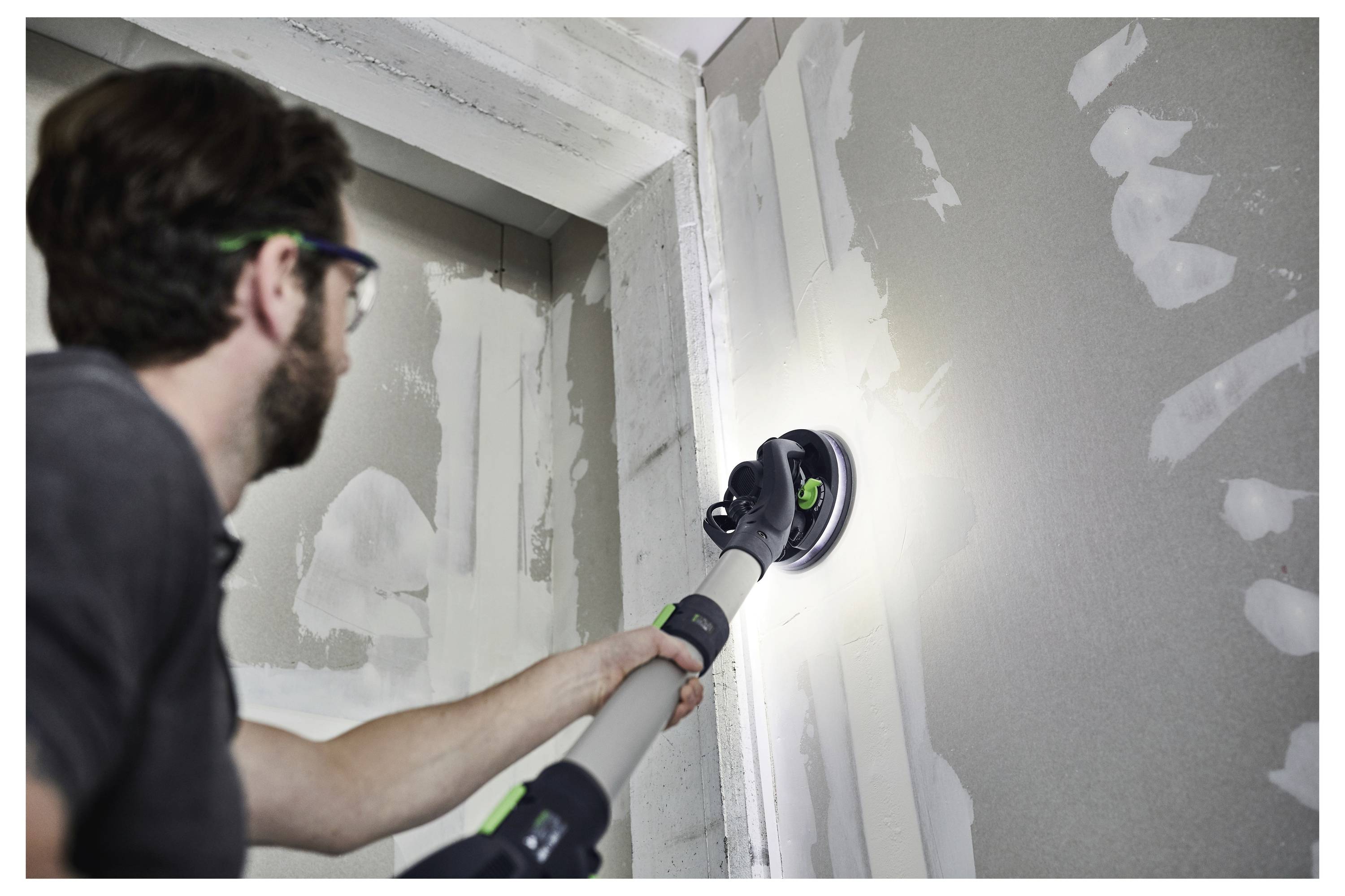 Una persona che indossa una cintura portautensili aziona una levigatrice elettrica portatile con un disco blu, illustrando l'uso in un contesto di falegnameria o costruzione.