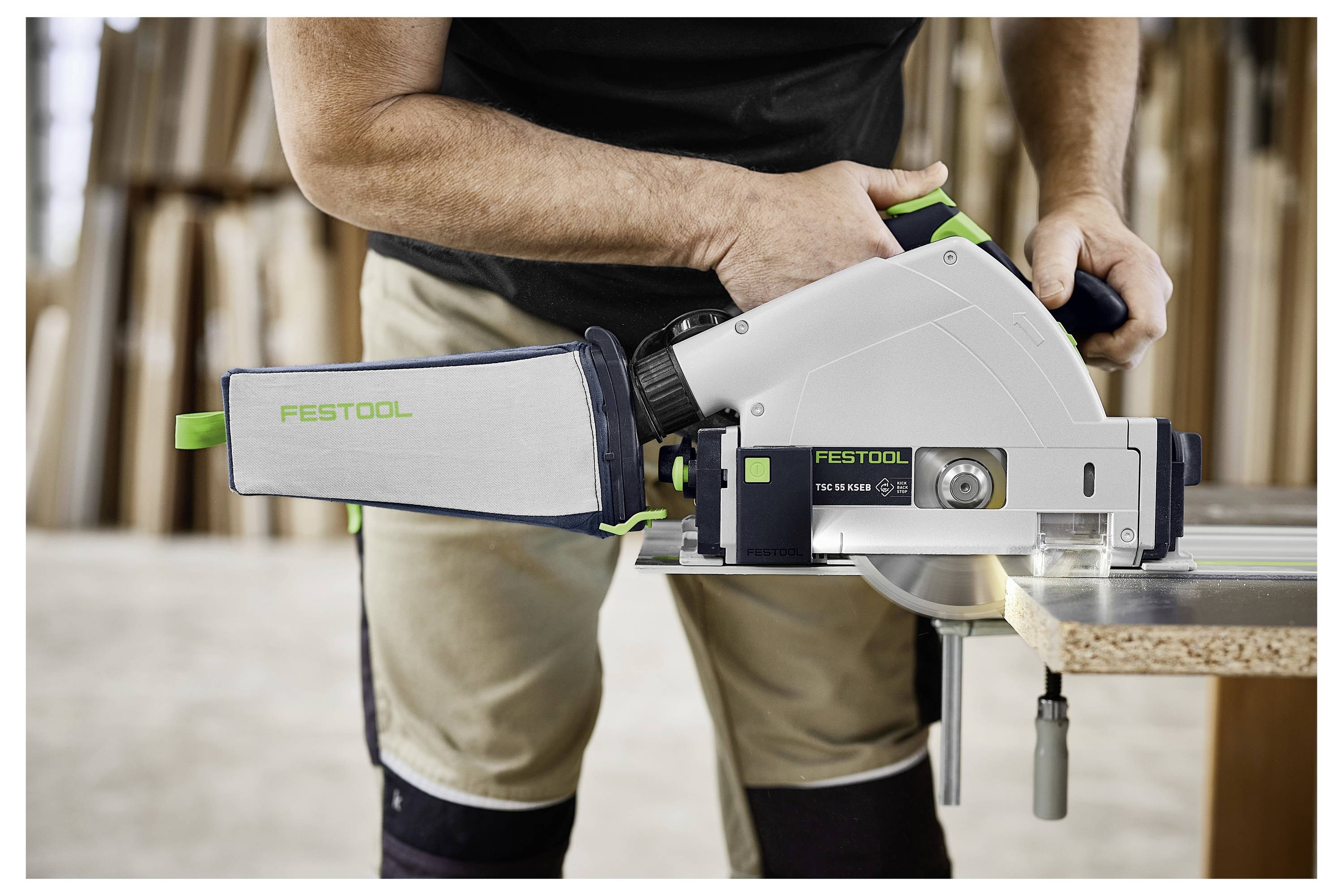 Una mano regola un attacco trasparente per l'estrazione della polvere su un router Festool OF 1400 EBQ posizionato su una superficie in legno, dimostrando la configurazione dello strumento.