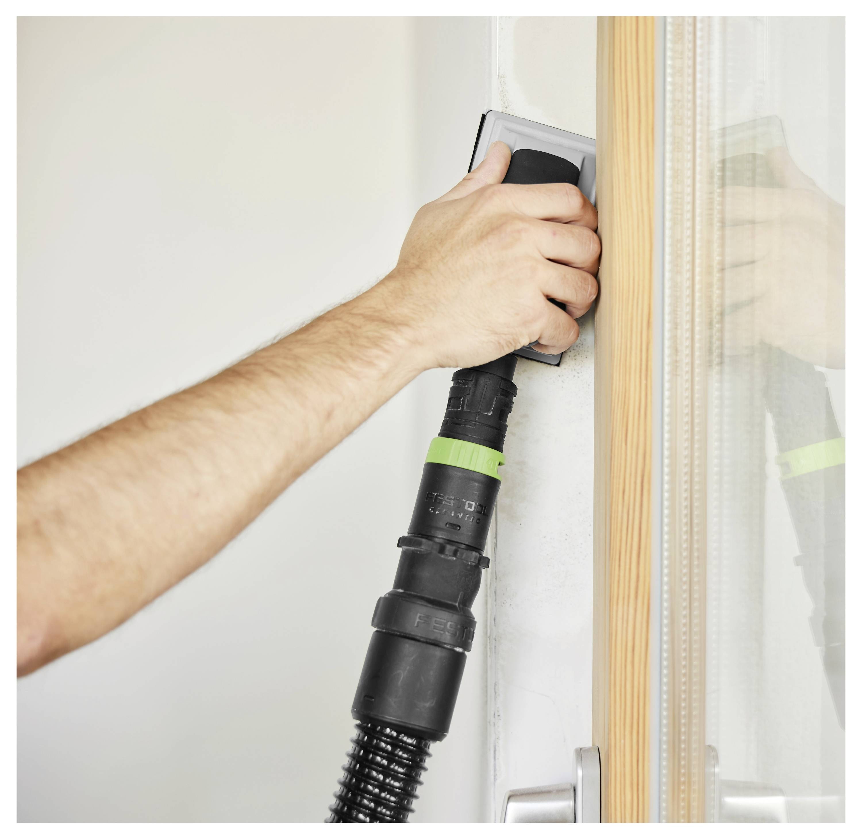 Un uomo che indossa occhiali di sicurezza sta utilizzando un utensile elettrico per modellare il legno in un laboratorio, circondato da vari attrezzi e materiali su scaffali.