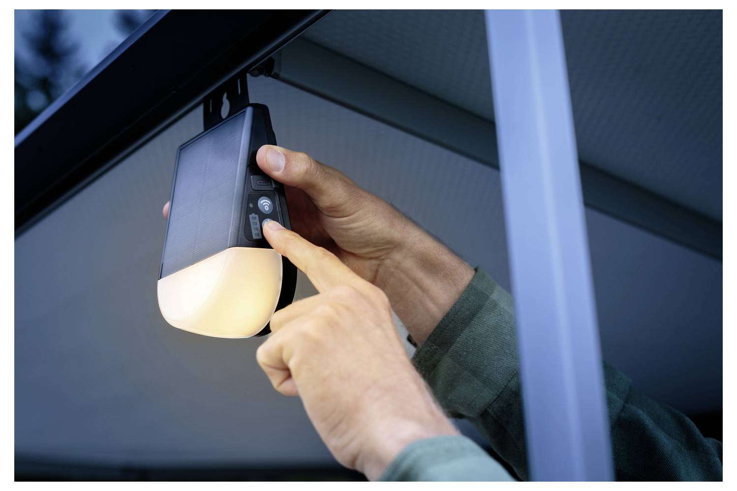 Una persona regola le impostazioni su un'apparecchiatura di illuminazione esterna installata.