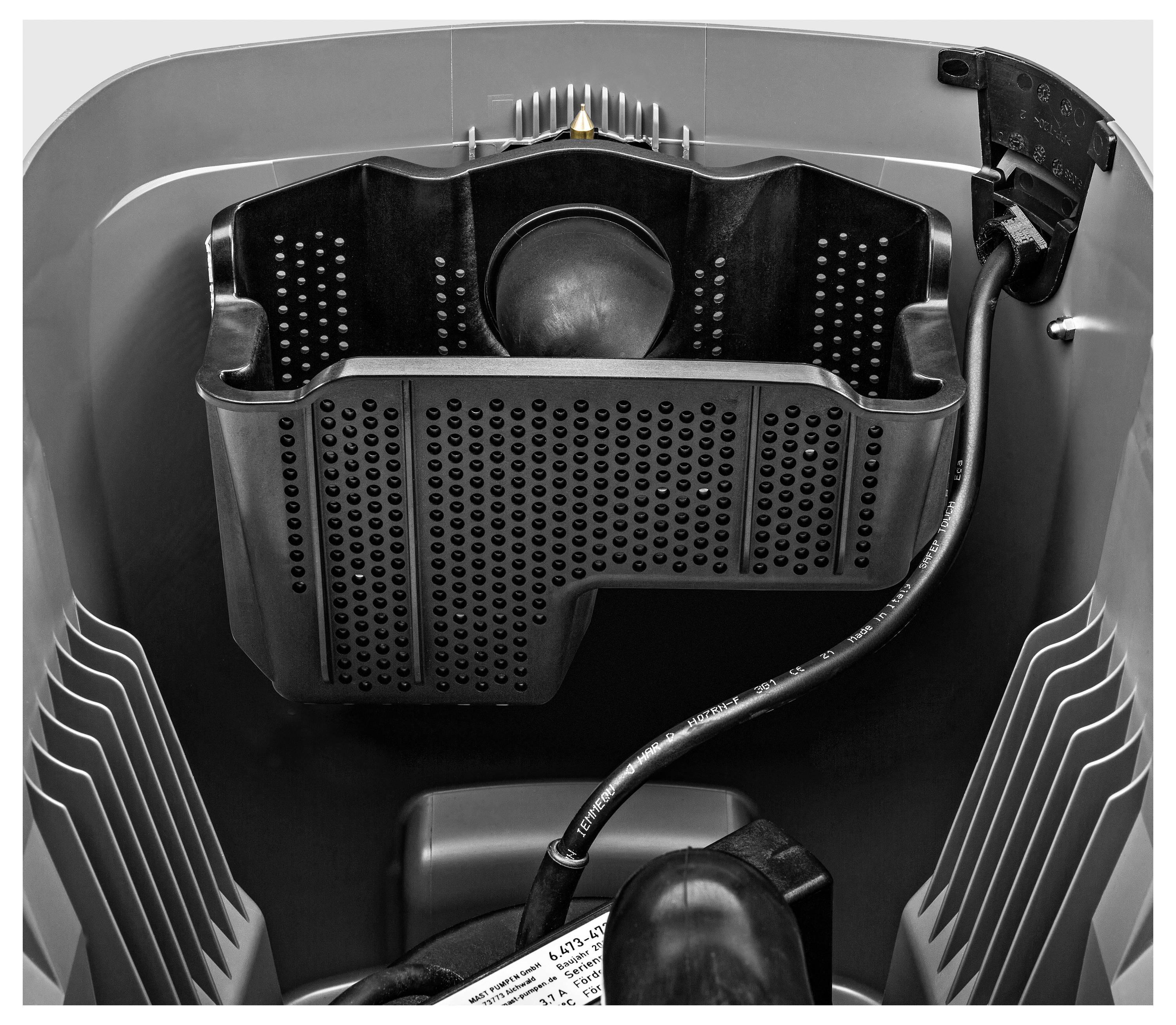 Una vista ravvicinata del cestello di una lavatrice con un compartimento di drenaggio nero distinto e tubo, che evidenzia il design interno e la texture.