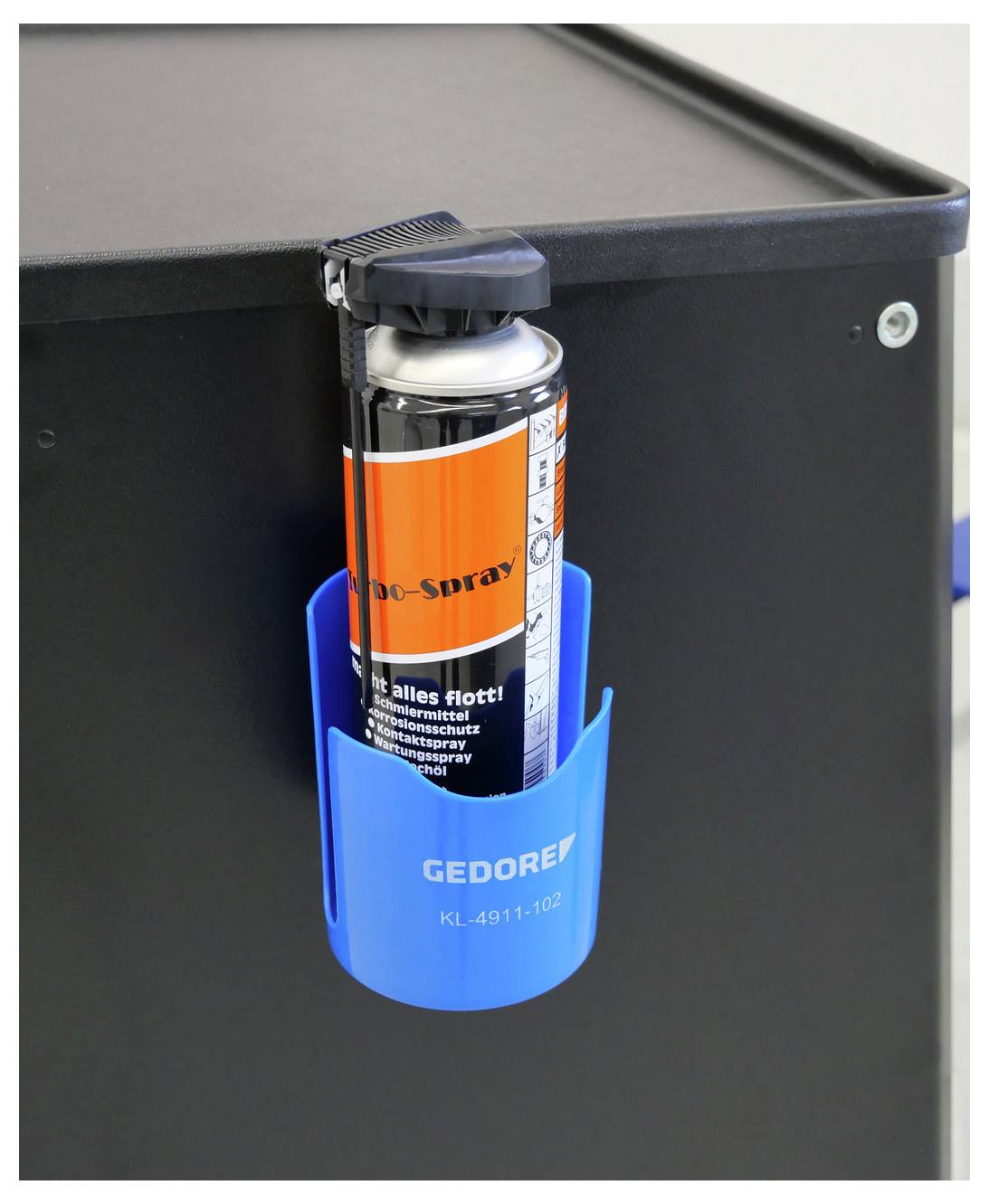 Bomboletta spray in supporto blu attaccato a superficie nera. Supporto etichettato GEdore K.L. 4911.102. Per organizzare attrezzi o forniture.