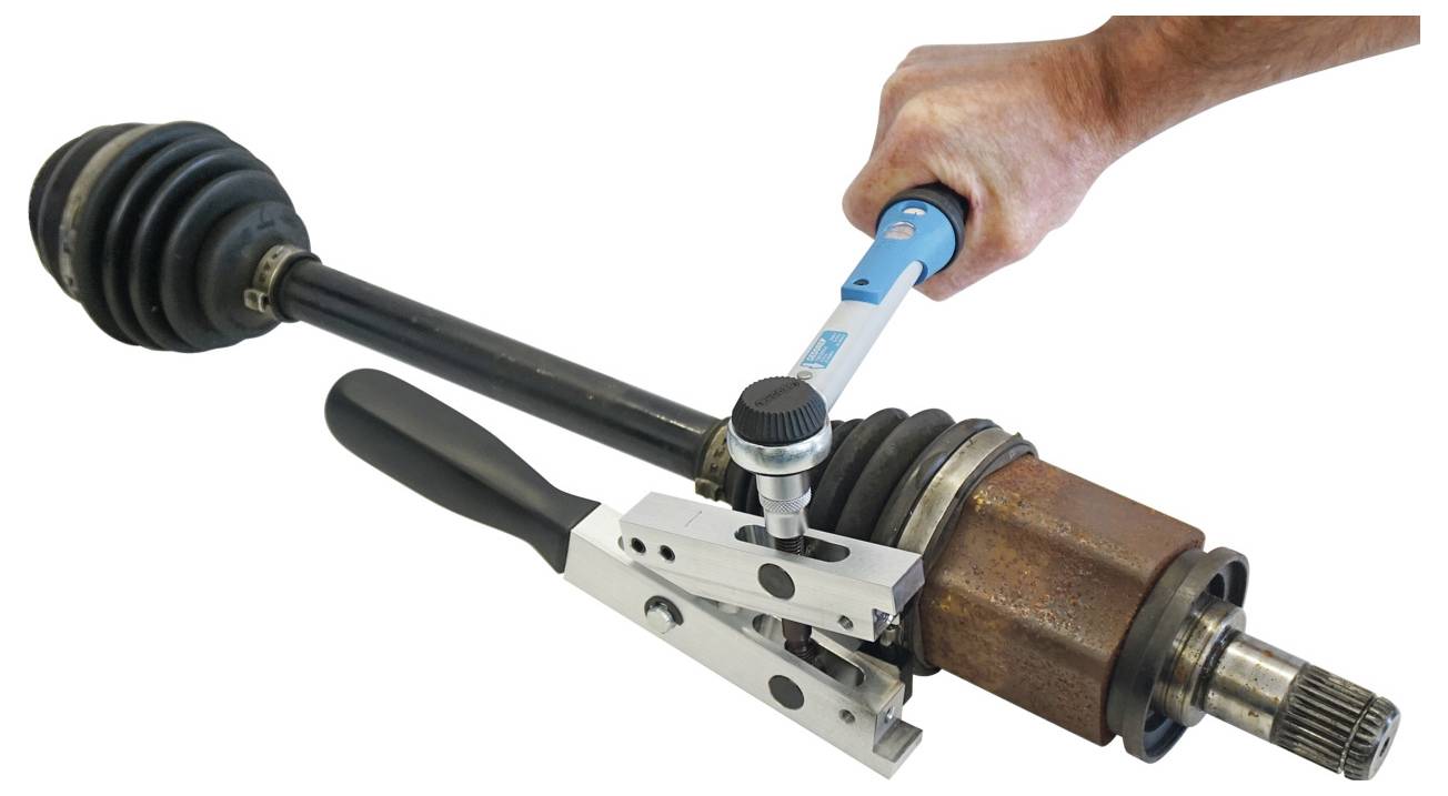 Una persona utilizza una chiave dinamometrica blu per serrare un dispositivo metallico su un asse del veicolo, dimostrando l'installazione o la manutenzione di una parte.