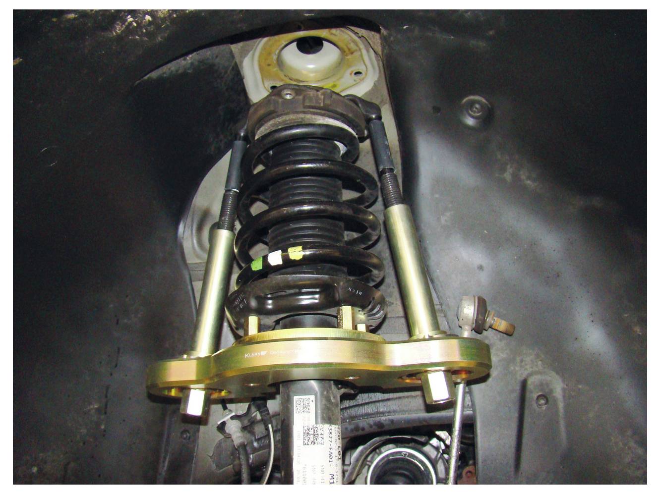 'Vista ravvicinata del sistema di sospensione di un'auto, che evidenzia la molla elicoidale e l'ammortizzatore all'interno della nicchia della ruota.'