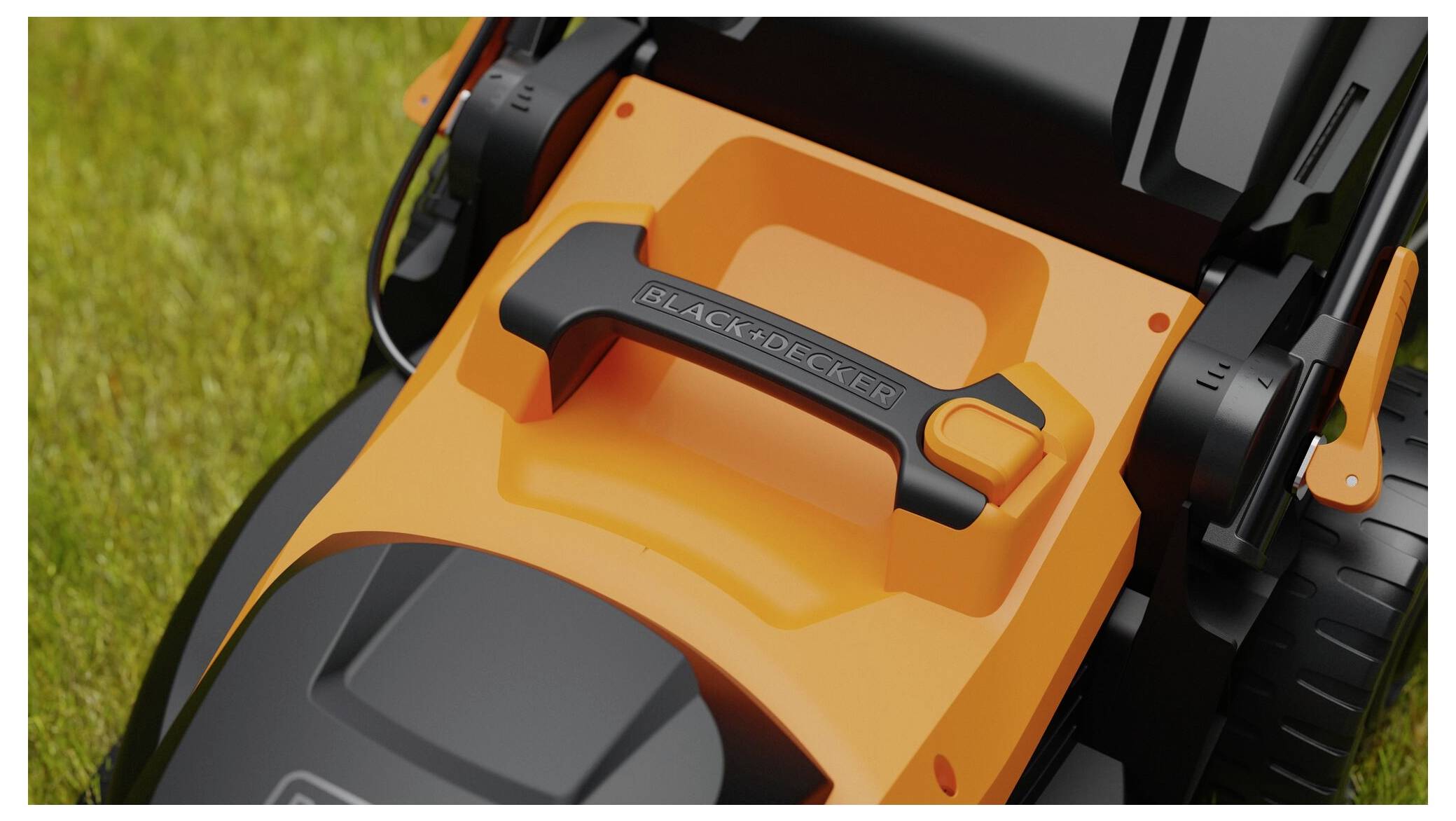 Un primo piano di un manico di un tosaerba nero e arancione sull'erba, che mostra il logo del marchio sul manico.