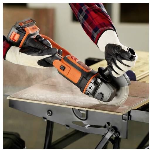 Una persona che indossa guanti utilizza una smerigliatrice angolare senza fili arancione e nera per tagliare un pezzo di legno su un banco da lavoro, dimostrando competenze di falegnameria.