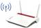 'Un router FritzBox con due antenne e spie luminose è mostrato accanto a un simbolo di segnale Wi-Fi blu.'
