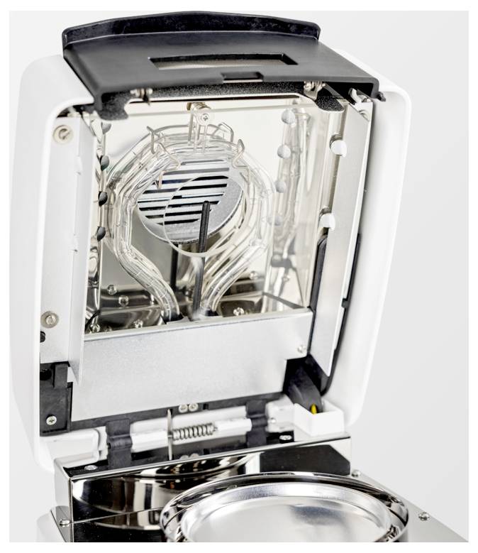 L'immagine mostra un dispositivo di laboratorio aperto con superfici riflettenti e un complesso cablaggio interno, che suggerisce attrezzature di precisione per uso scientifico.