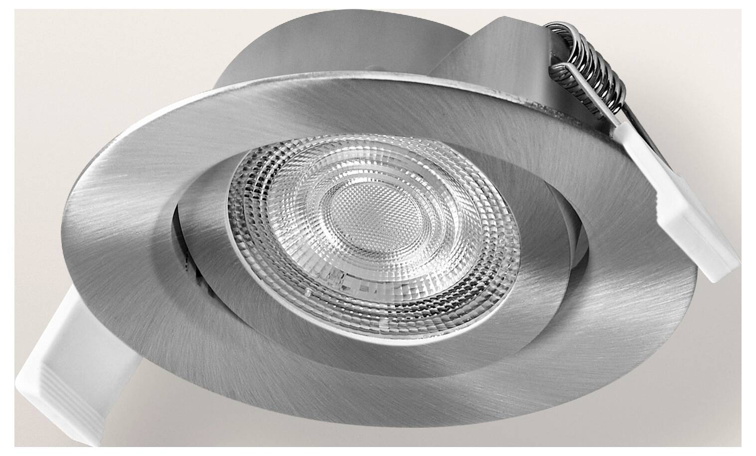 Un'apparecchio di illuminazione da incasso a soffitto in argento con lente in vetro e bordo metallico, visto da sotto in angolazione.