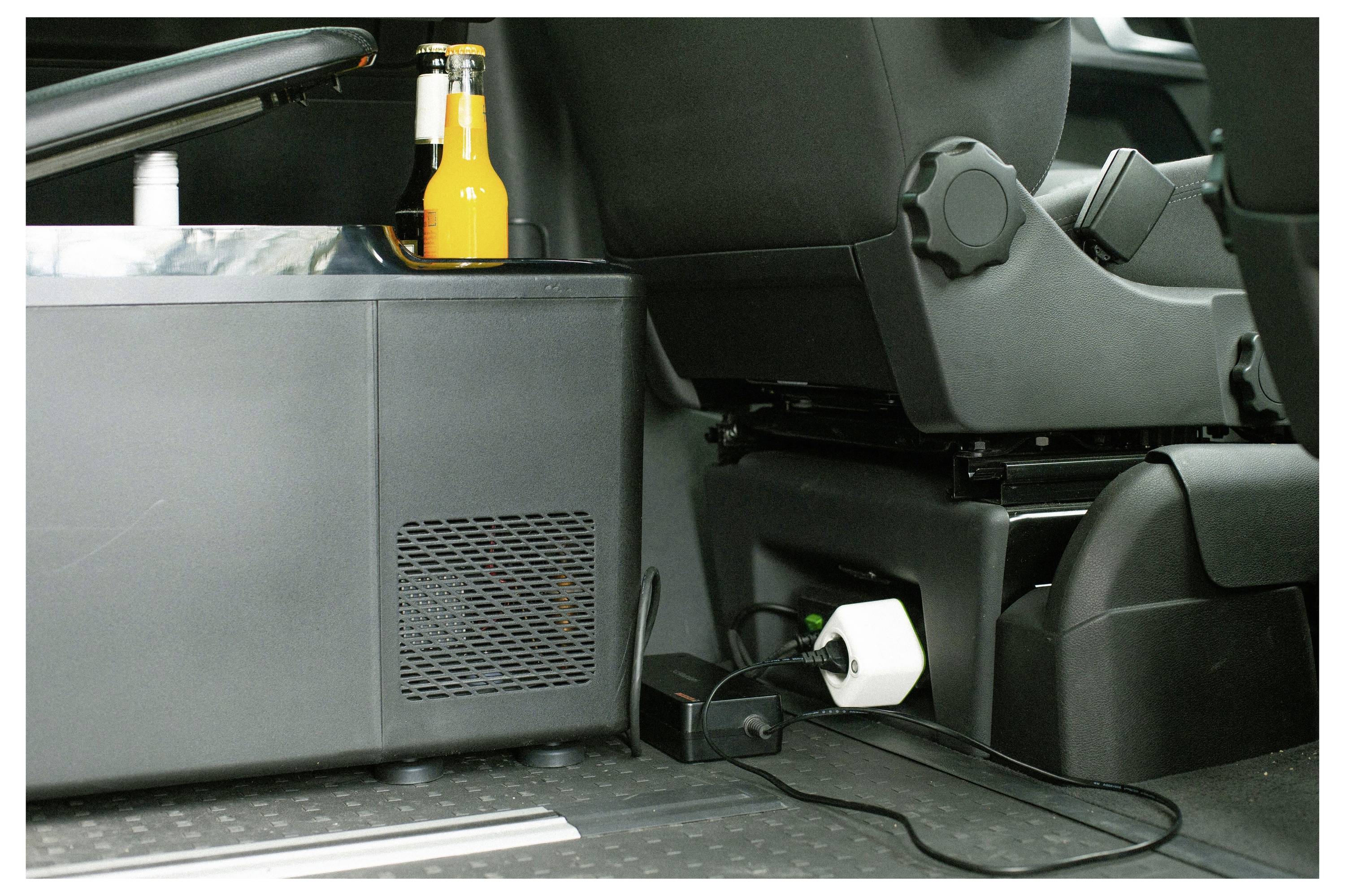 All'interno di un veicolo, un piccolo frigorifero è posizionato sul pavimento accanto al sedile posteriore, con due bevande in bottiglia riposte sopra.
