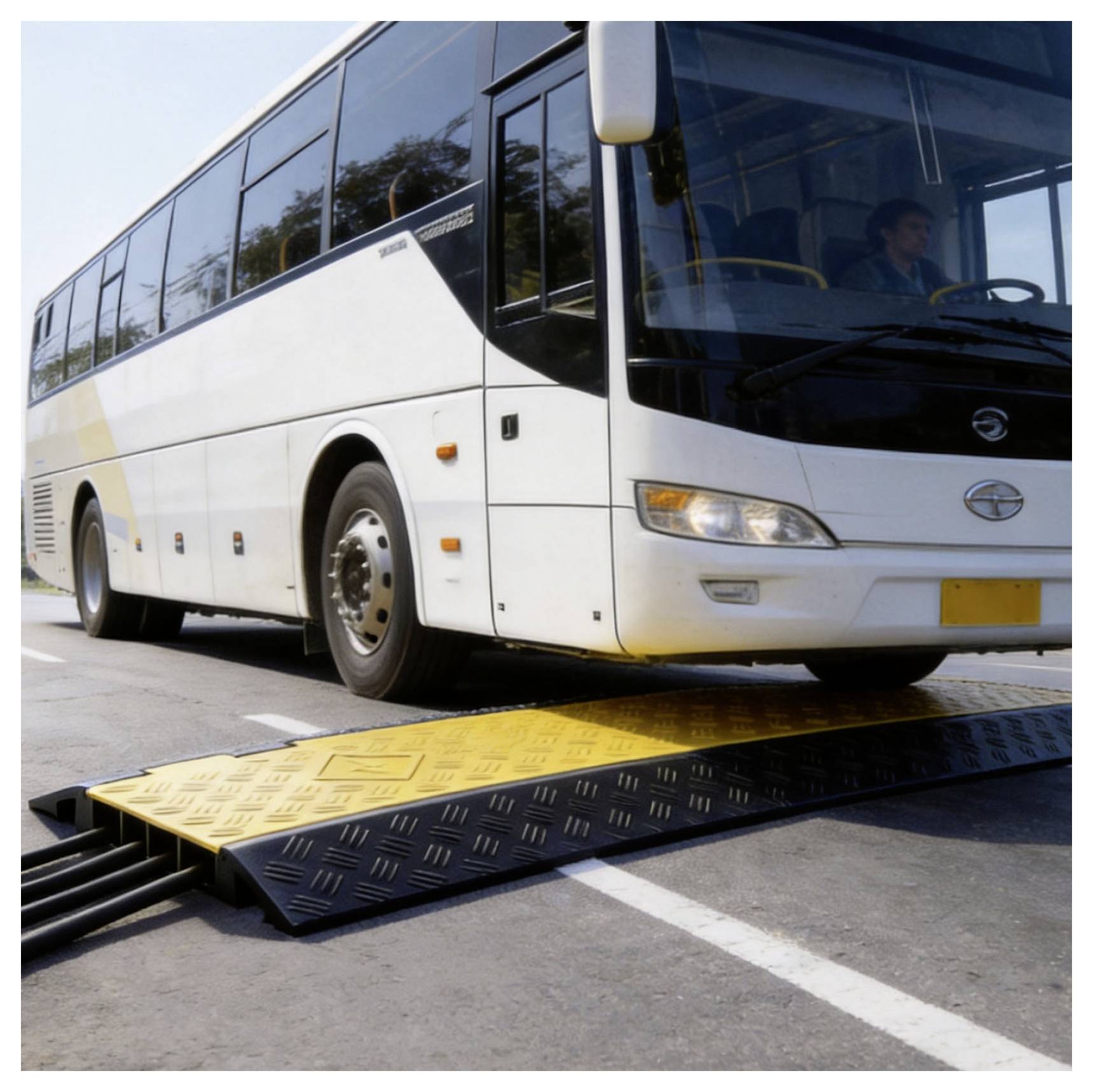 Autobus passeggeri bianco che passa sopra una buca di rallentamento giallo-nera su una strada.