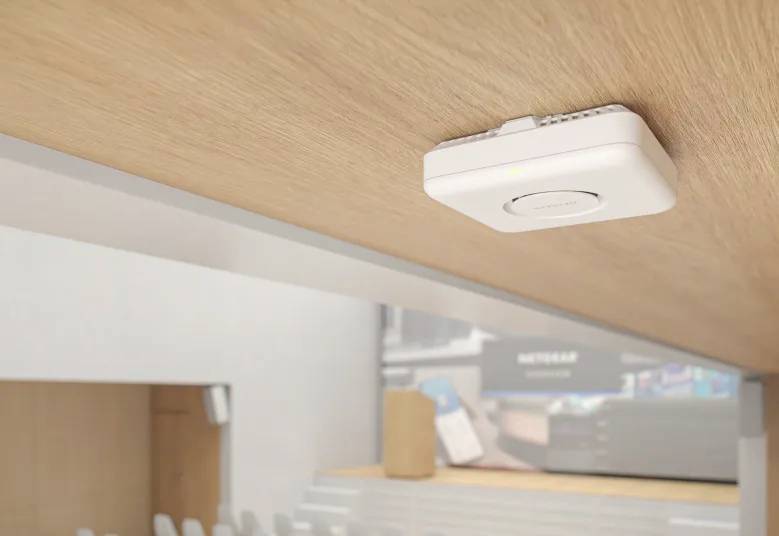 Un punto di accesso wireless è montato su un soffitto in legno in una moderna sala conferenze, fornendo connettività Internet.
