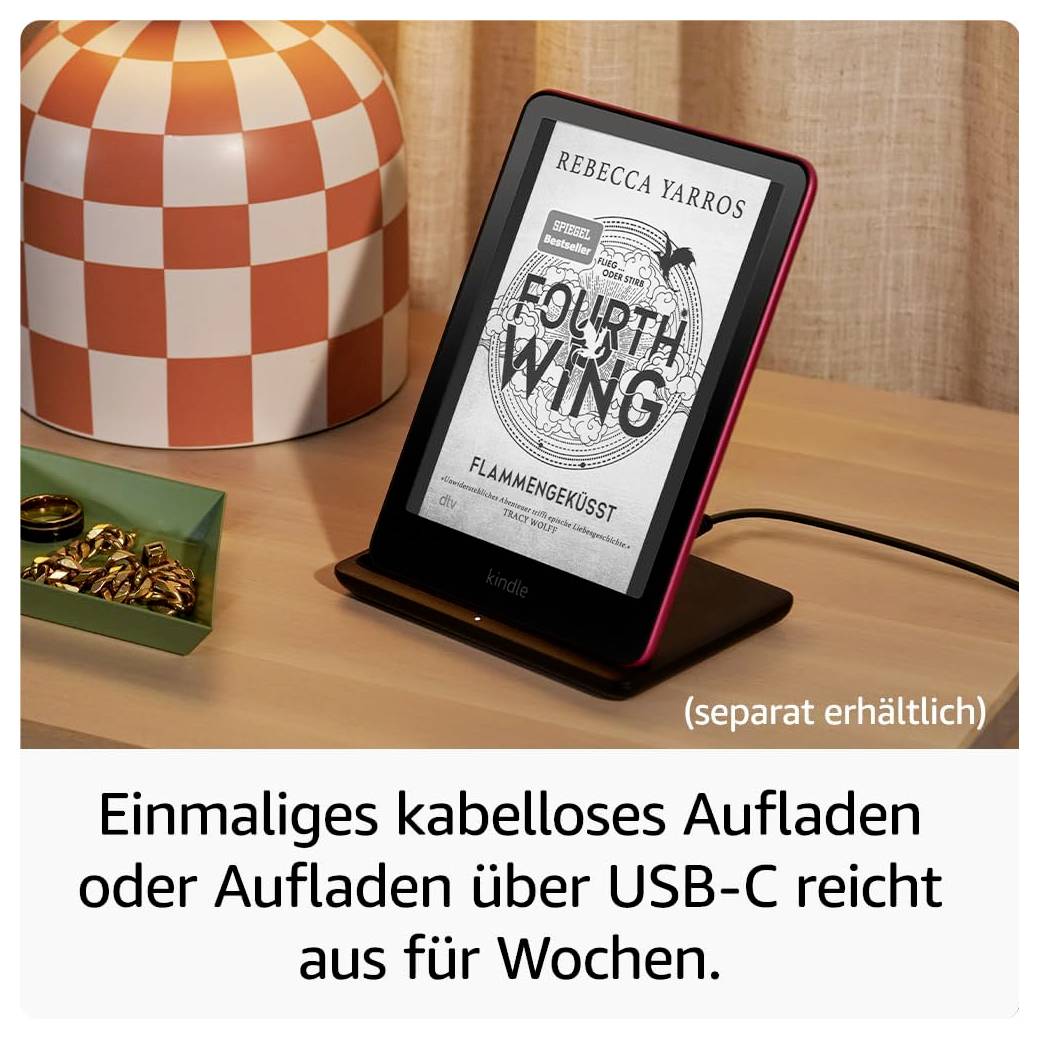 Un lettore di eBook su un tavolo mostra "Fourth Wing" di Rebecca Yarros. Accanto ad esso un caricabatterie wireless e decorazioni. Il testo descrive le opzioni di ricarica.