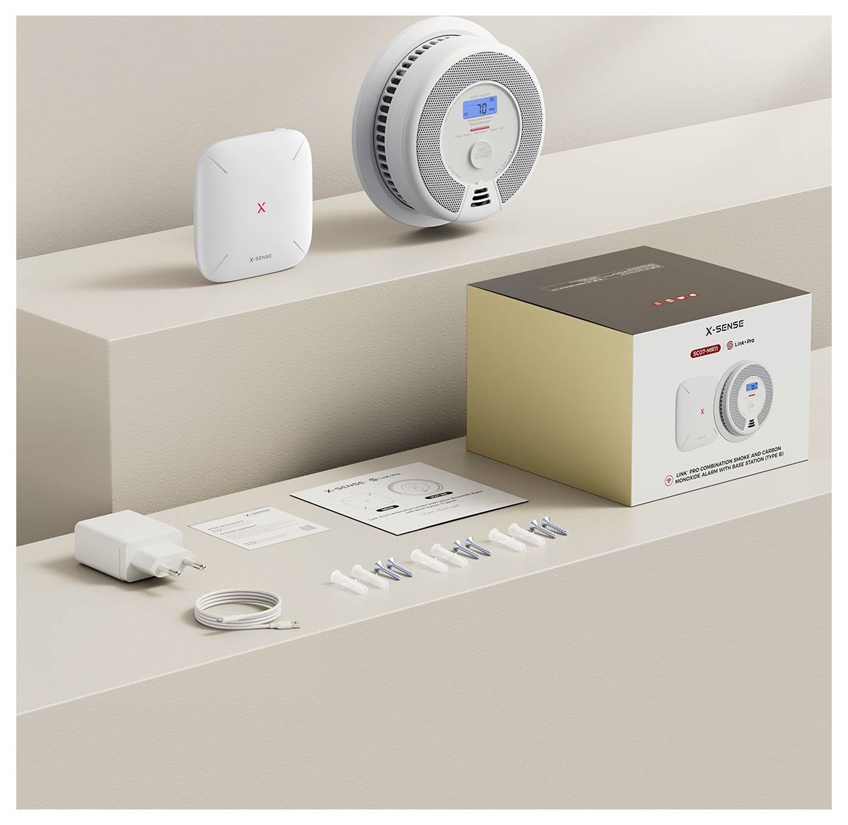 Un set di rivelatori di fumo con un rivelatore di fumo bianco, materiale di fissaggio, cavi, adattatore, manuale d'uso e imballaggio su un tavolo.