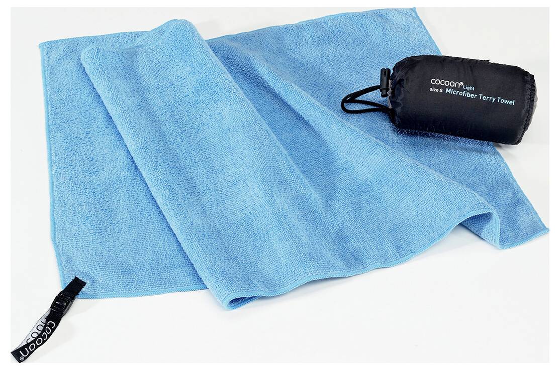 Un asciugamano in microfibra blu brillante giace piatto accanto alla sua compatta borsa di stoccaggio nera, etichettata con il marchio e il tipo di prodotto.