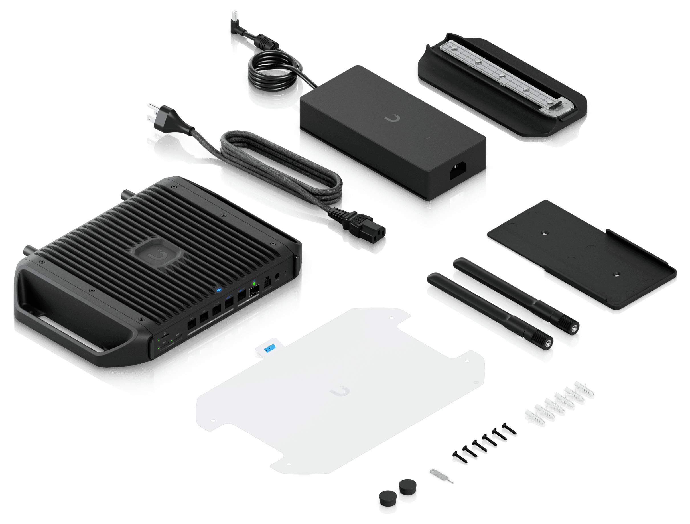 Un kit di tecnologia smontato che presenta un hub principale, un alimentatore, antenne, viti, staffe di montaggio e cavi, disposti su una superficie bianca.