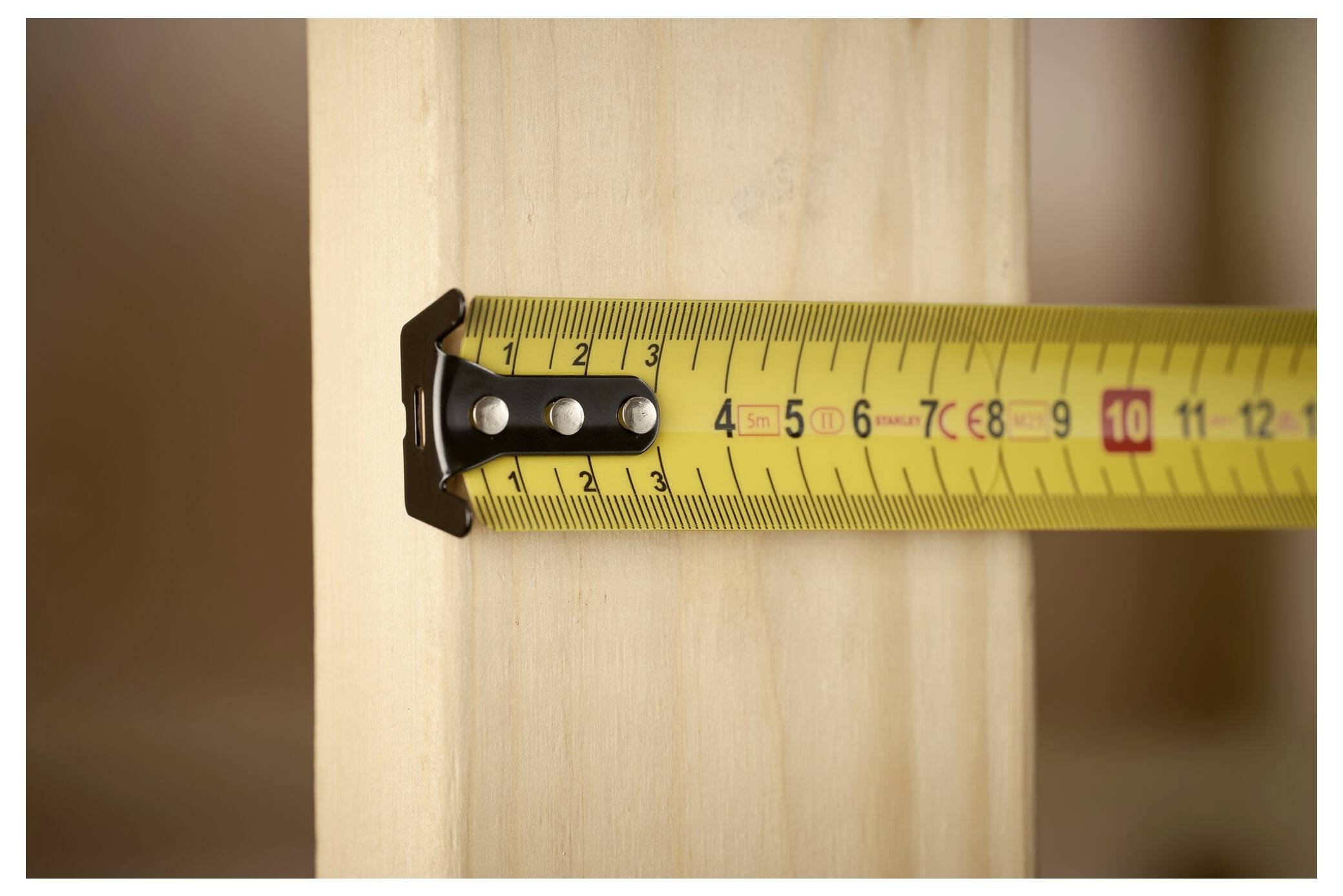 Un metro a nastro esteso su legno, che mostra 10 cm.