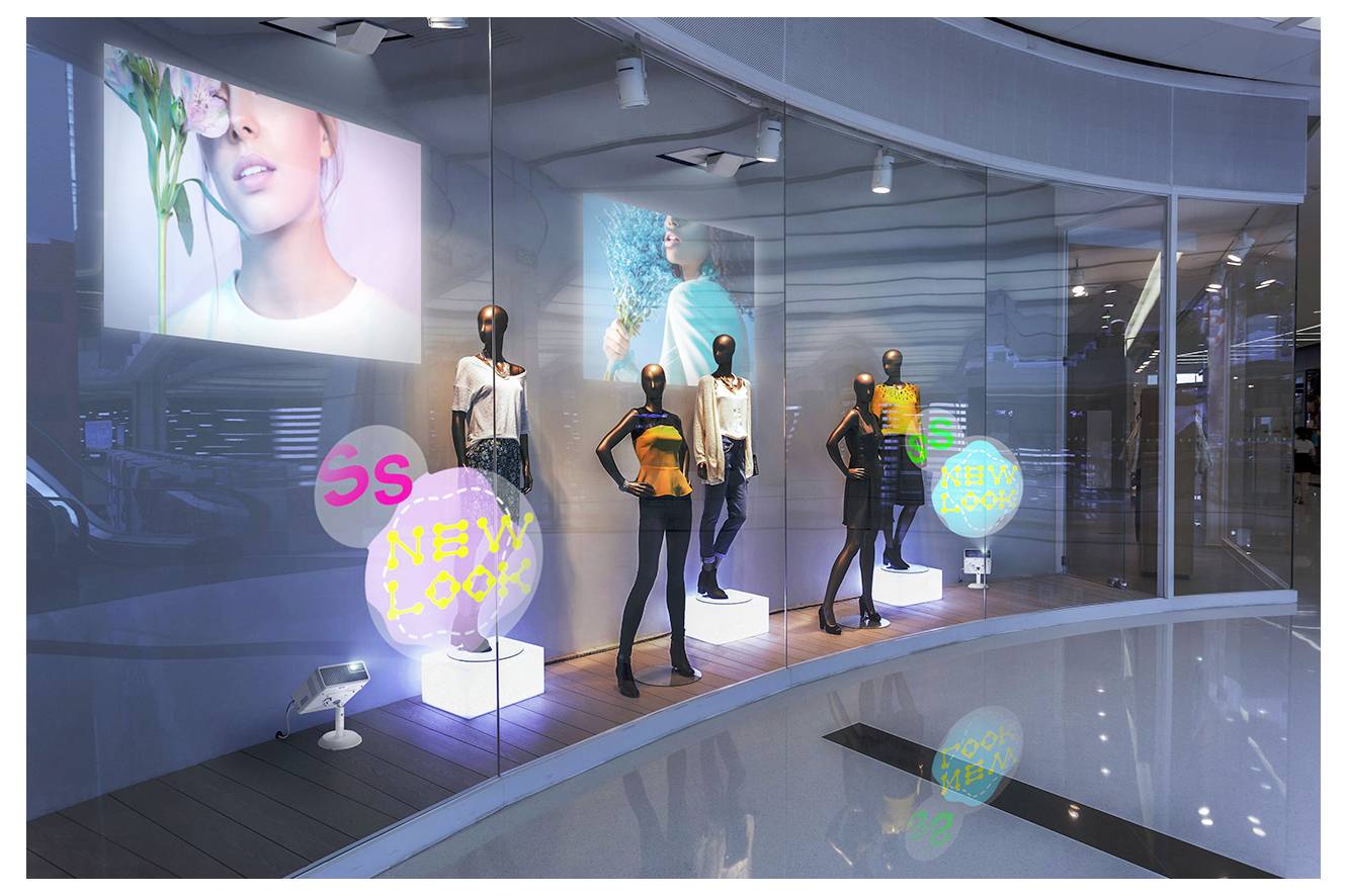 Vetrina di negozio di moda con manichini vestiti in abbigliamento moderno e insegne al neon "NEW LOOK", posizionati dietro vetro curvo con grandi poster di moda.