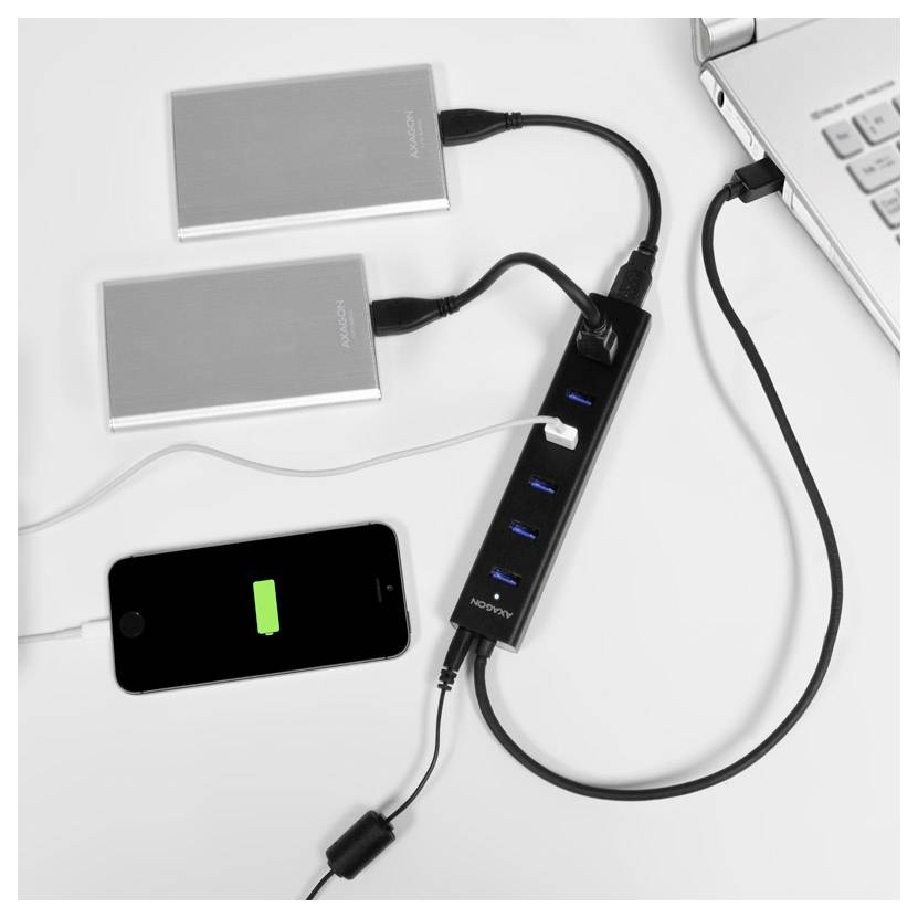 Due unità esterne e uno smartphone sono collegati a un hub USB accanto a un laptop, con il telefono che mostra un'icona di batteria in carica.
