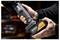 Mani che tengono un pacco batteria per utensili cordless DeWalt etichettato "McLaren" e "DEWALT", mostrato in primo piano in un ambiente di laboratorio.