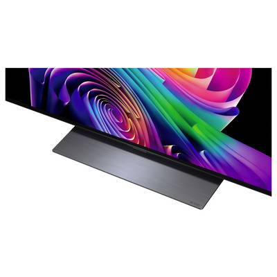 Un elegante monitor a schermo piatto visualizza un vivace turbine astratto di colori arcobaleno su uno schermo nero, mostrato con un supporto in metallo spazzolato.