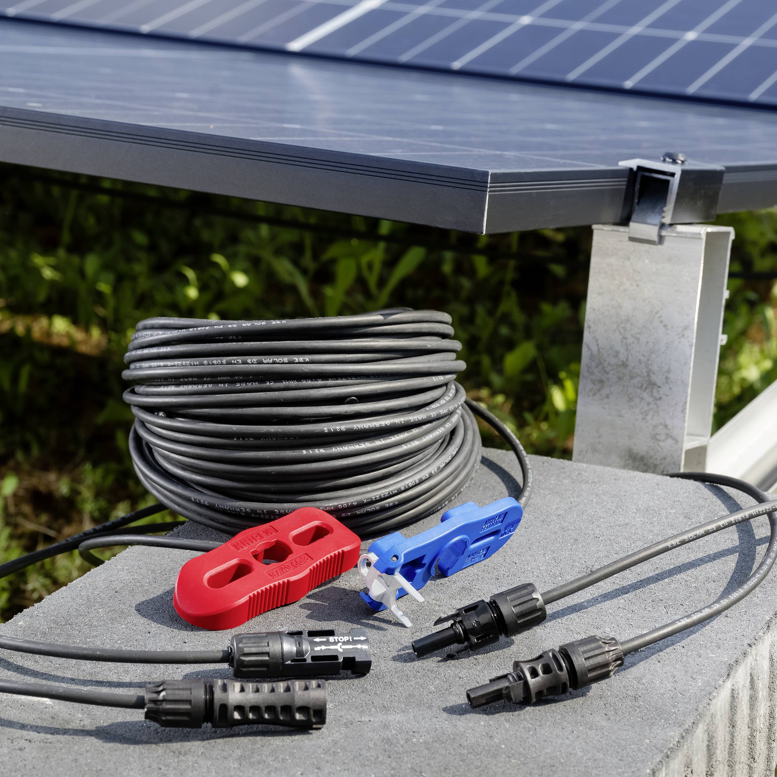 Montaggio di pannello solare con cavo nero arrotolato e connettori elettrici rossi, blu e neri su una base in cemento.