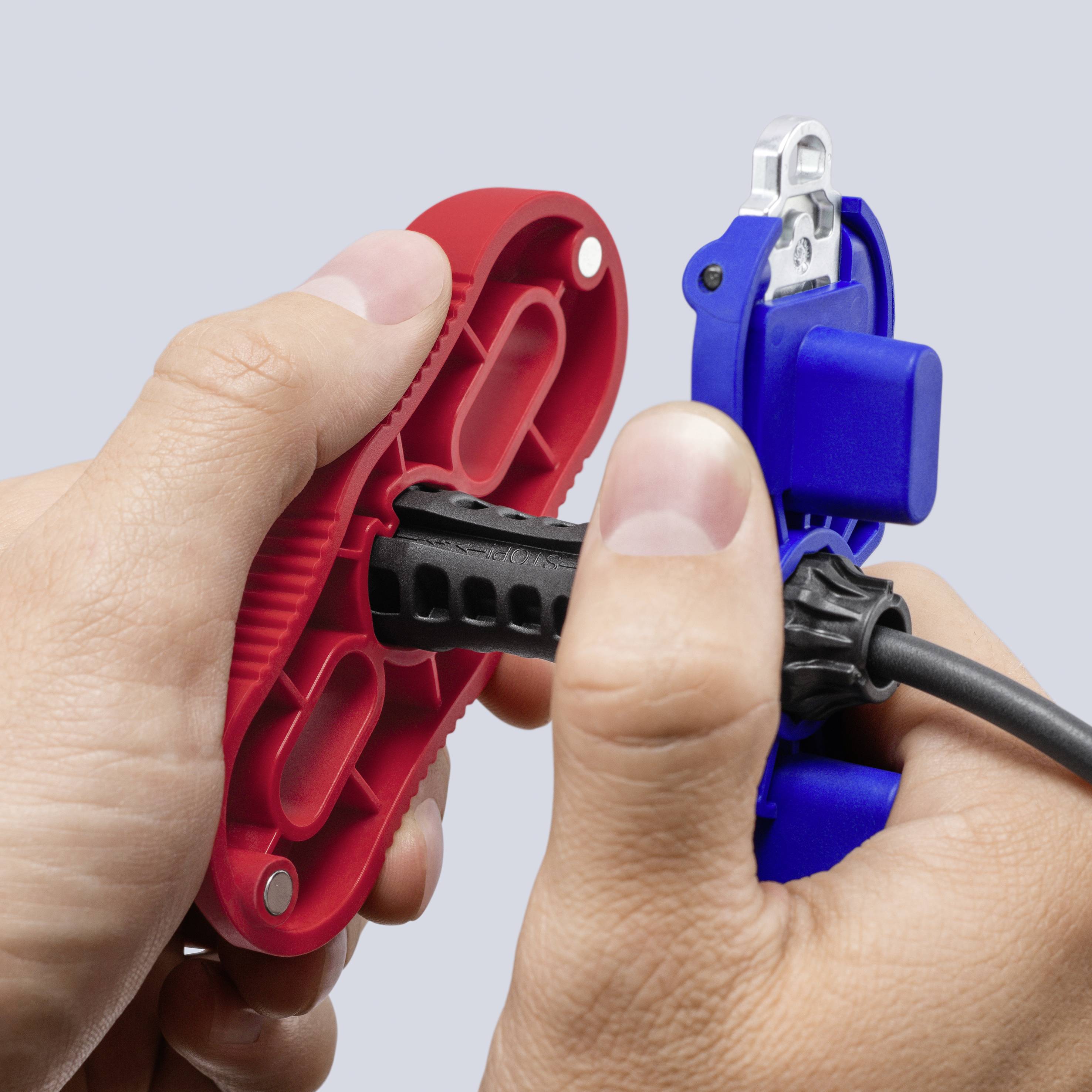 Mani che assemblano un cavo elettrico nero in connettori di filo rossi e blu, mostrando una spina o una connessione di riparazione del cavo.